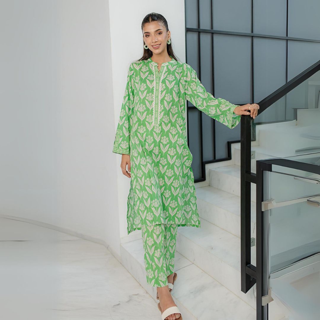 Woman wearing green floral printed ready to wear Pakistani dresses UK standing on white staircase indoors