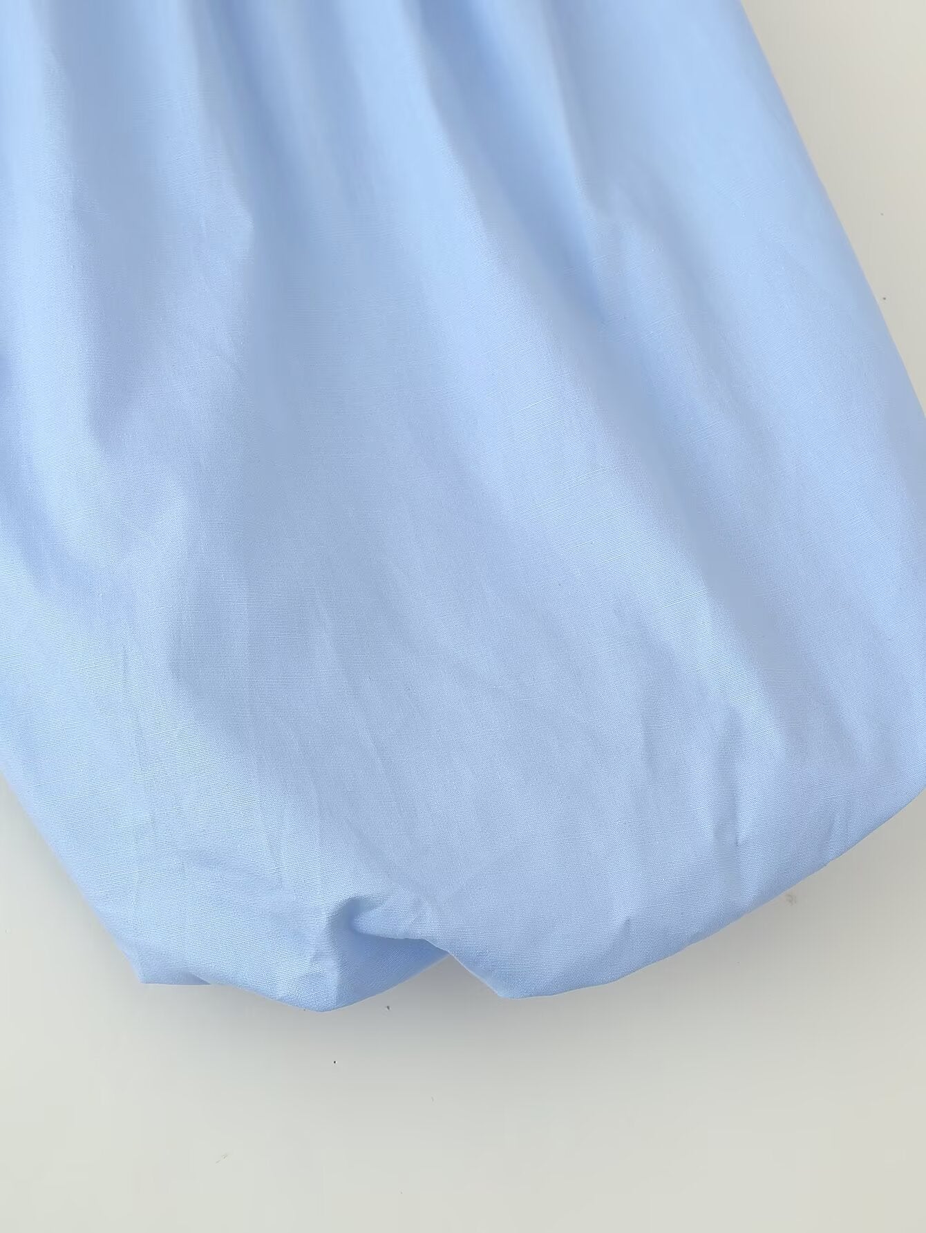 Close up of light blue fabric puff sleeve round neck maxi dress showing gathered sleeve and hem