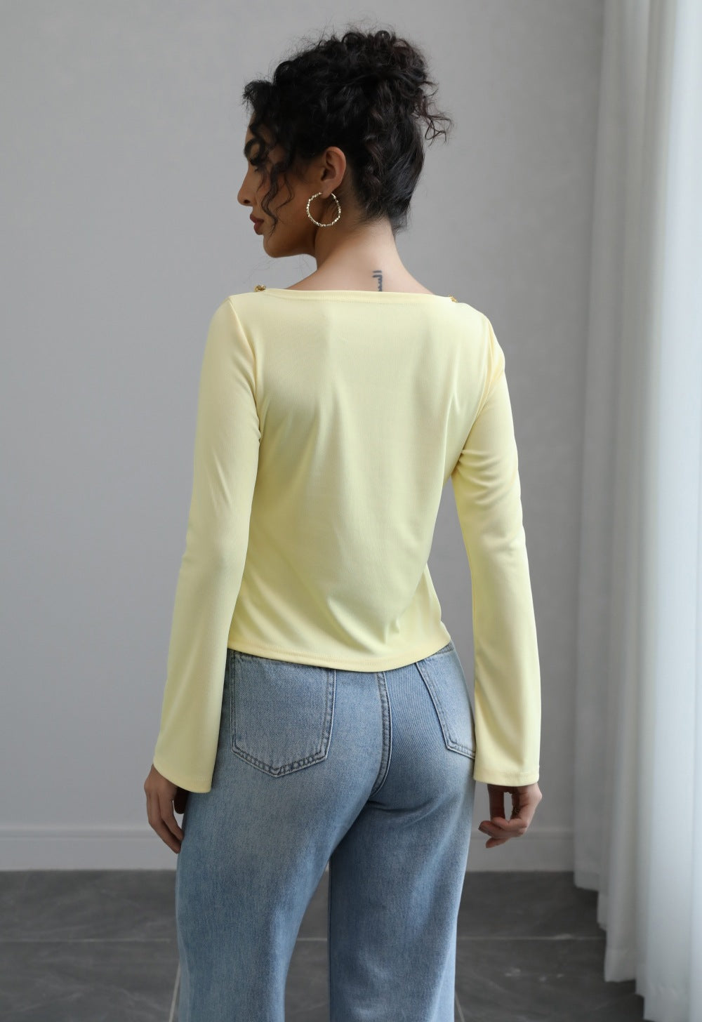Malbusaat autumn lace up top pale yellow long sleeve seen from back with light blue jeans and hoop earrings