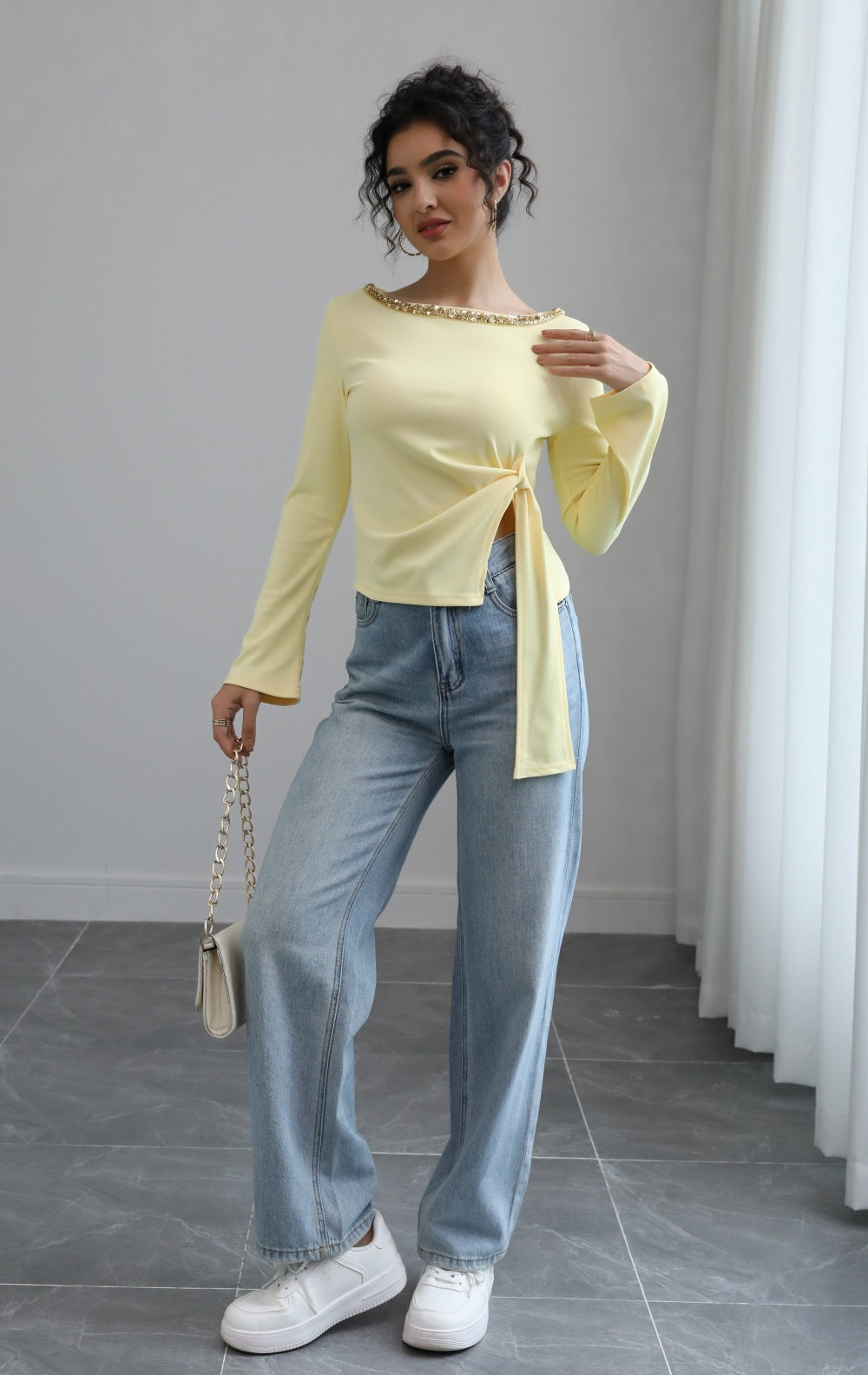 Malbusaat model wearing pale yellow autumn lace up top with side tie and beaded neckline paired with wide leg jeans