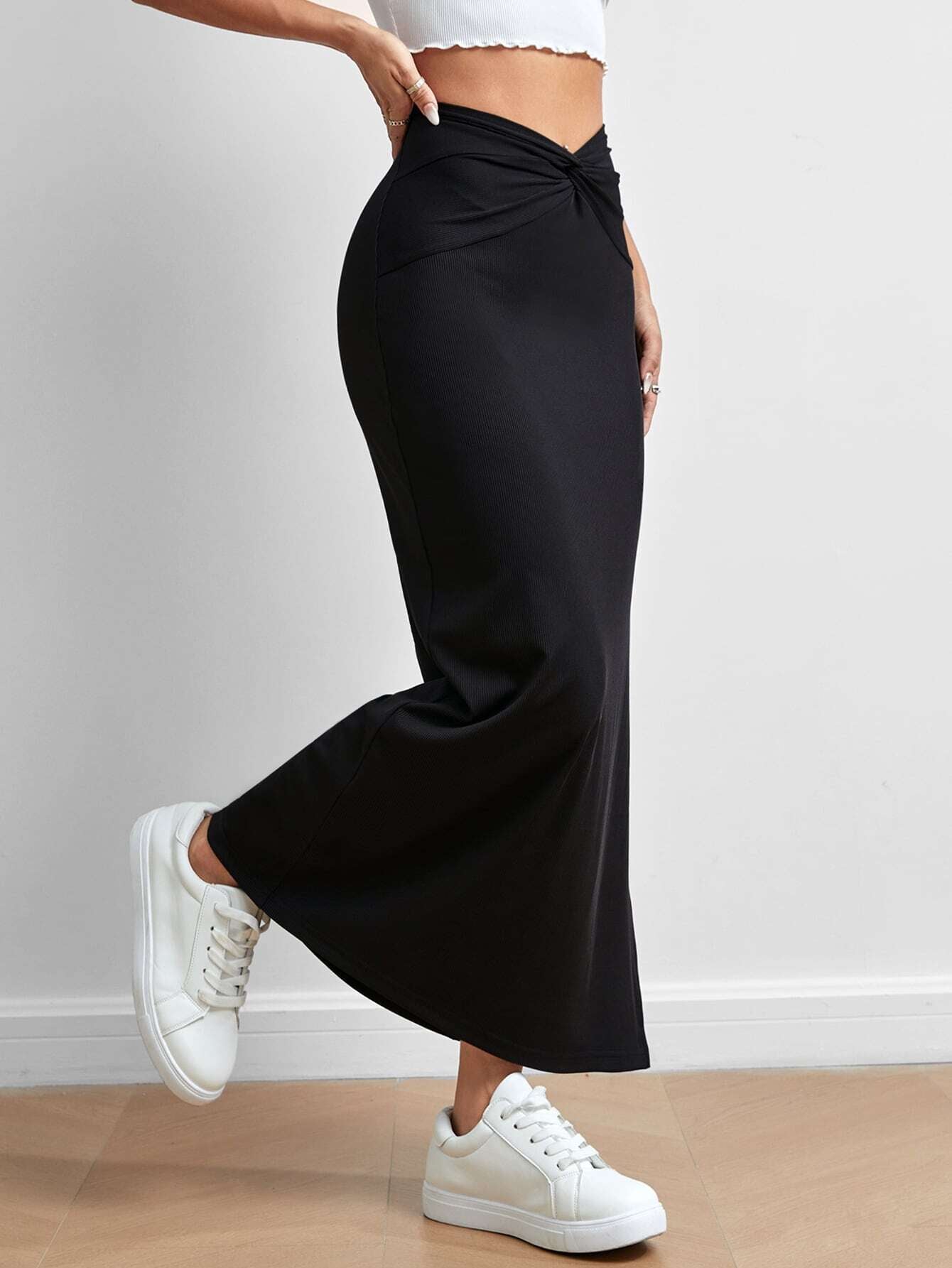 Black drape slit skirt by Malbusaat with twisted waist detail paired with white sneakers