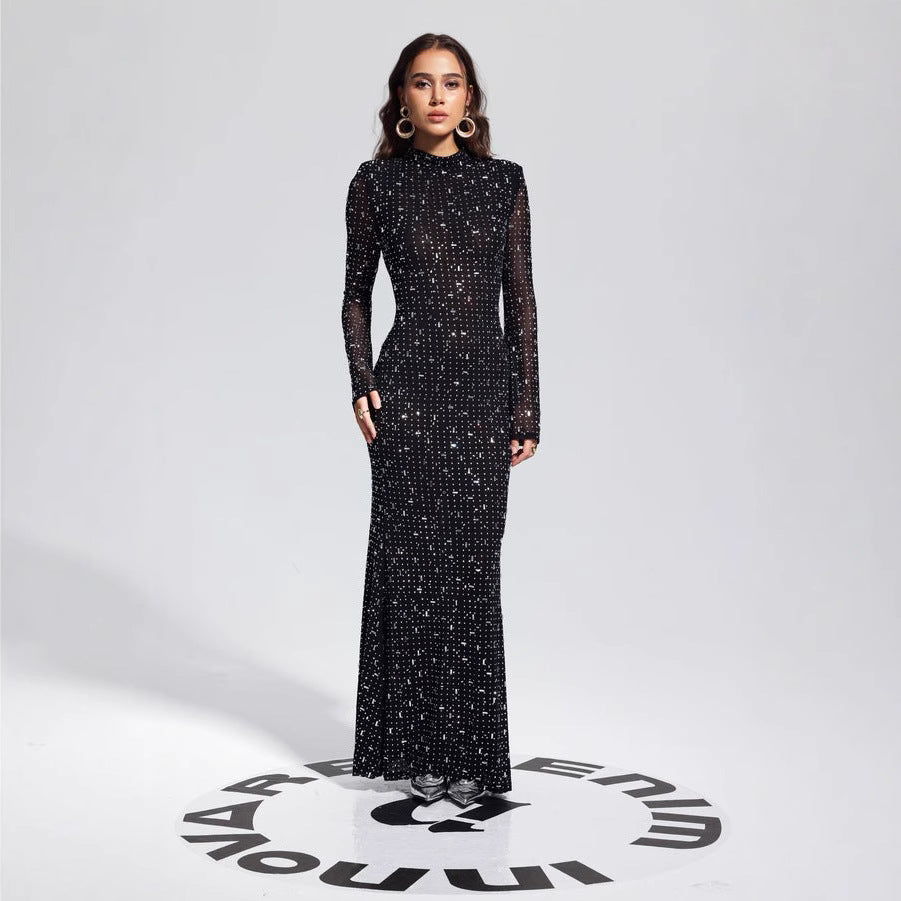 Malbusaat model wearing a floor length black rhinestone bodycon dress with long sleeves and high neck