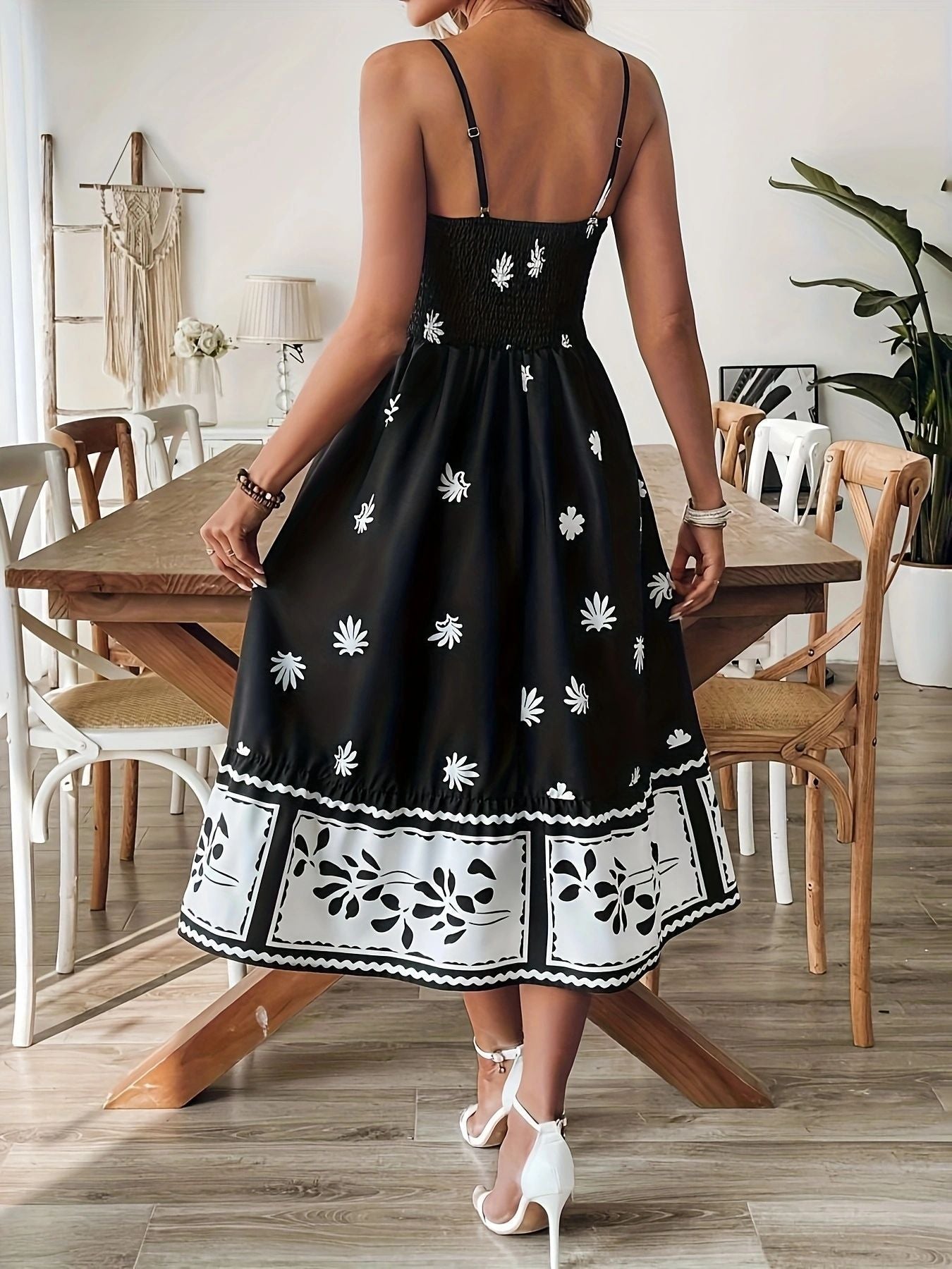 Back view of women's printed summer midi dress in black with white floral patterns and spaghetti straps