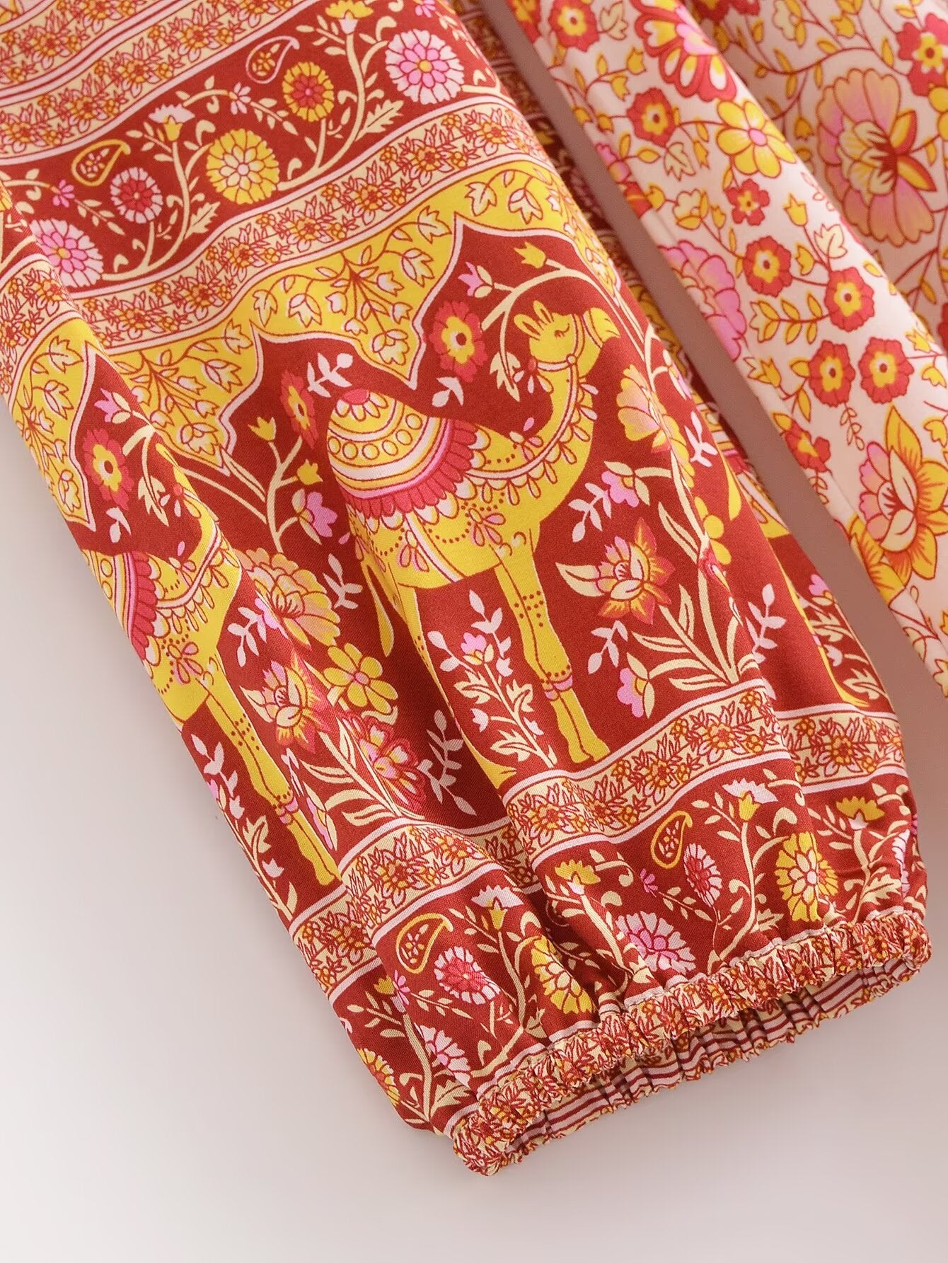 Close-up of Malbusaat rayon floral maxi dress sleeve with vibrant red and yellow floral and animal print