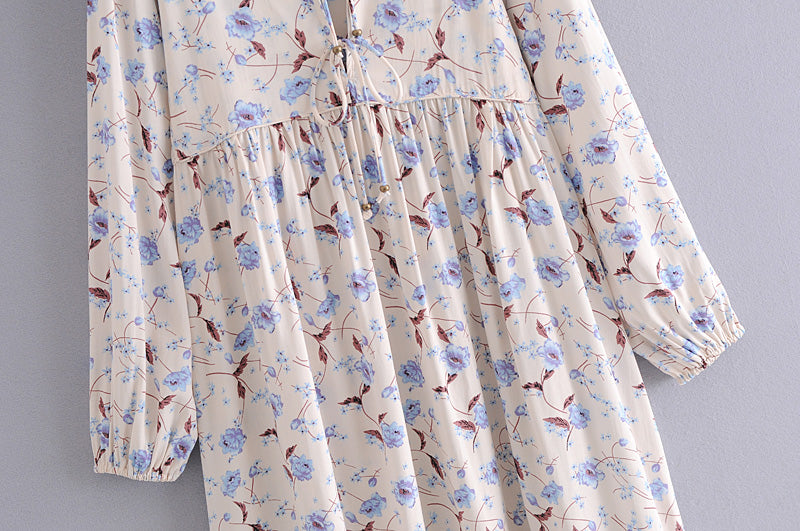 Elegant floral maxi dress by Malbusaat featuring delicate blue flowers and long sleeves on cream fabric