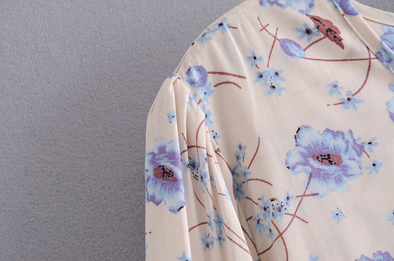 Close-up of elegant floral maxi dress fabric with purple and blue flowers on cream background