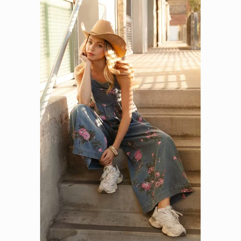 Floral denim jumpsuit for women styled casually with sneakers and a hat on sunny stairs