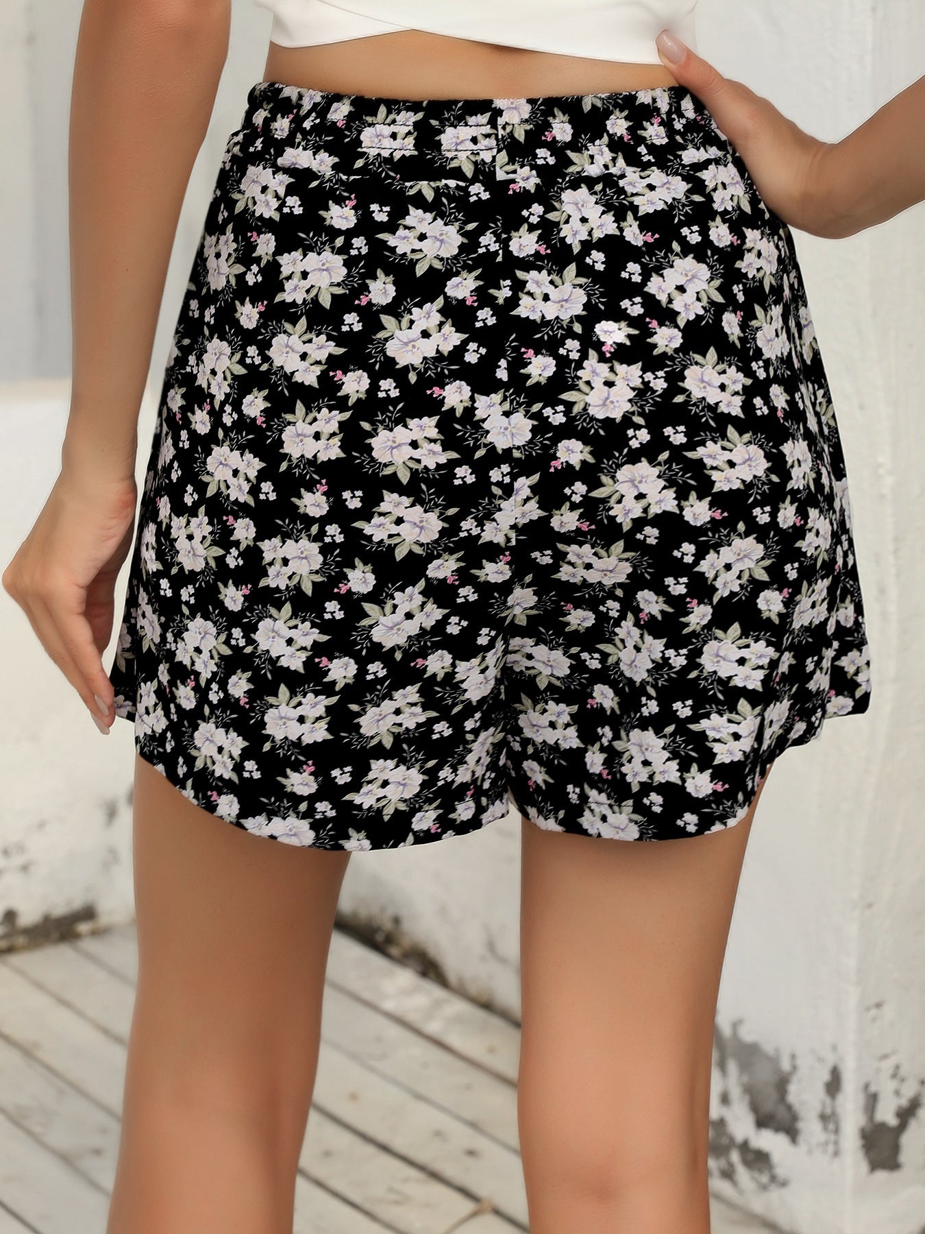 Back view of floral elastic waist shorts featuring a black background with white and pink floral pattern
