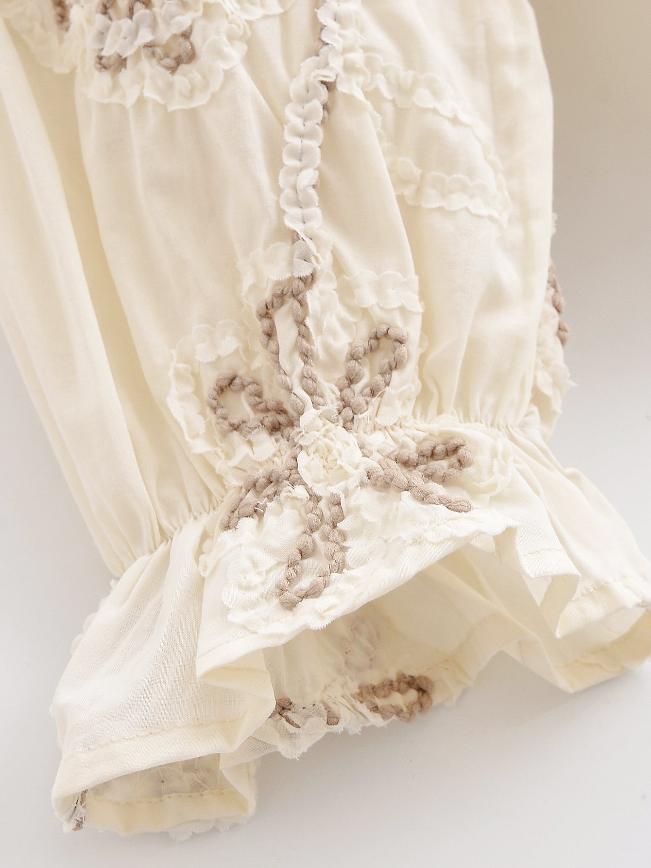 Close-up of delicate embroidery on cream floral mini shirt for women by Malbusaat with textured floral patterns