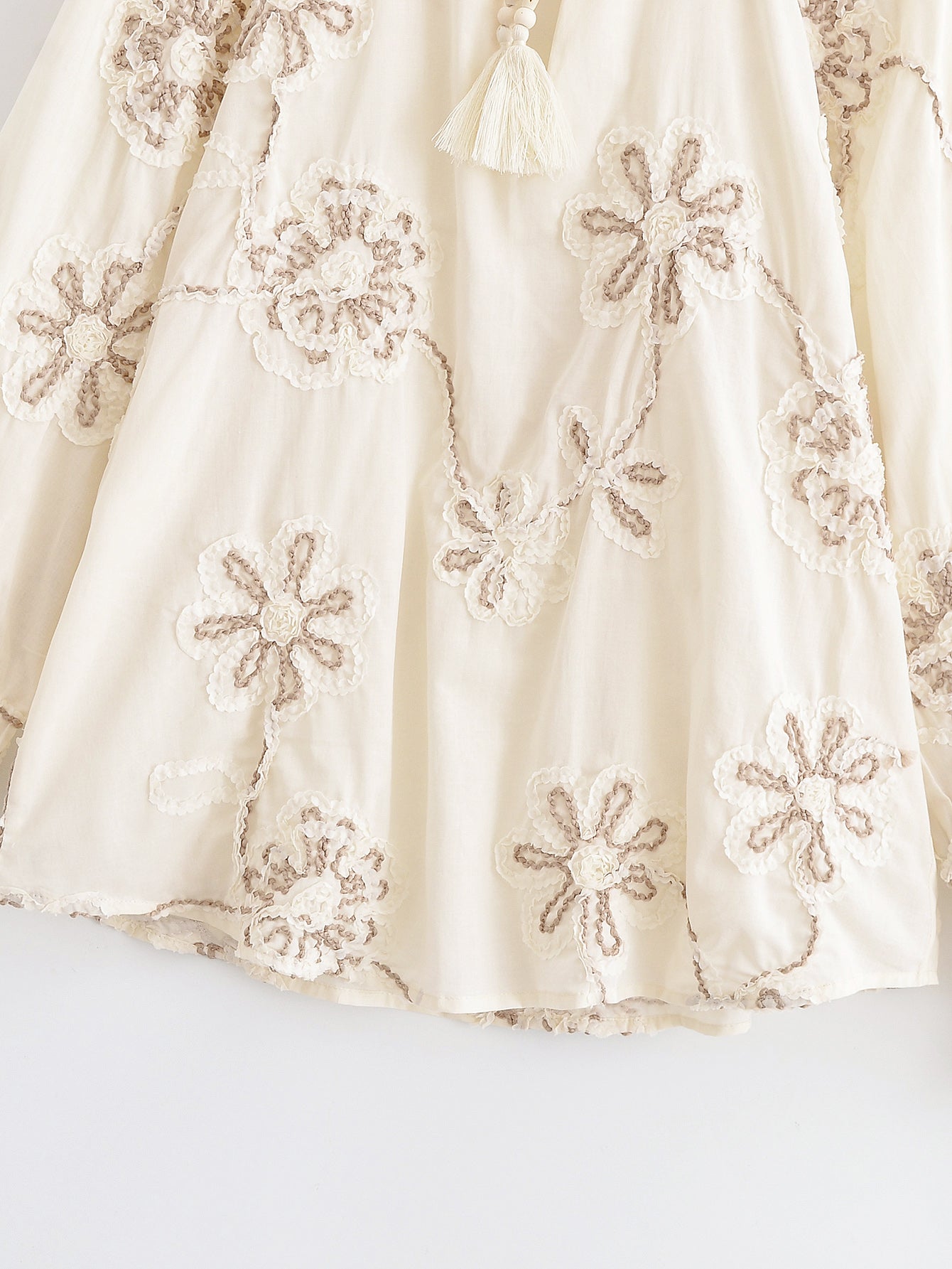 Close-up of cream floral mini shirt for women with delicate embroidered flower patterns by Malbusaat