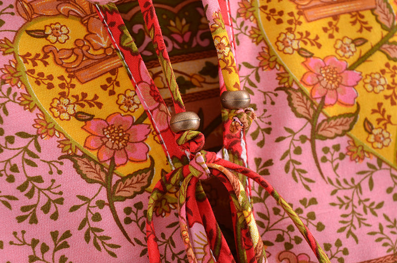 Close-up of floral patterned fabric with decorative ties and beads on spring long sleeve maxi dress by Malbusaat