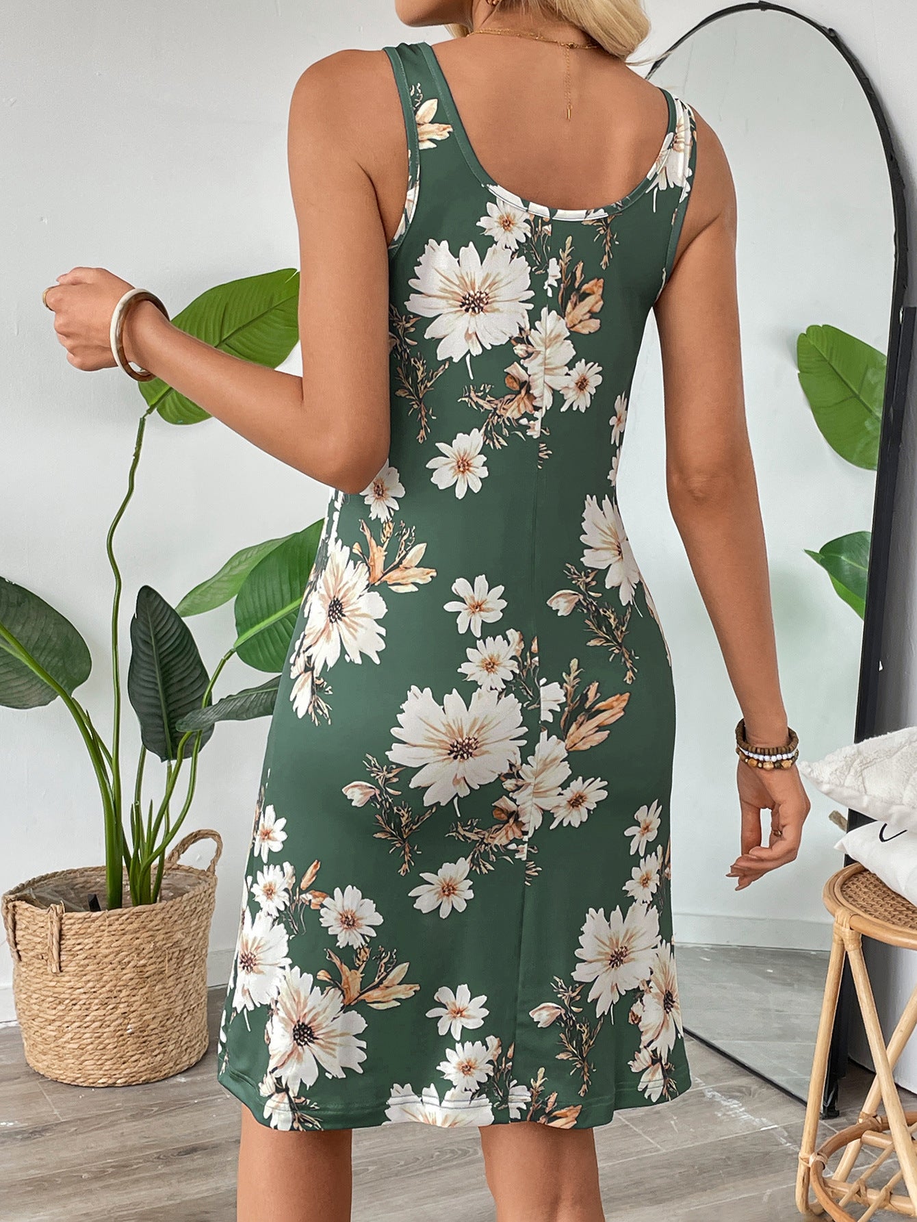 Back view of a woman wearing green floral spaghetti strap dress with white and beige flowers by Malbusaat
