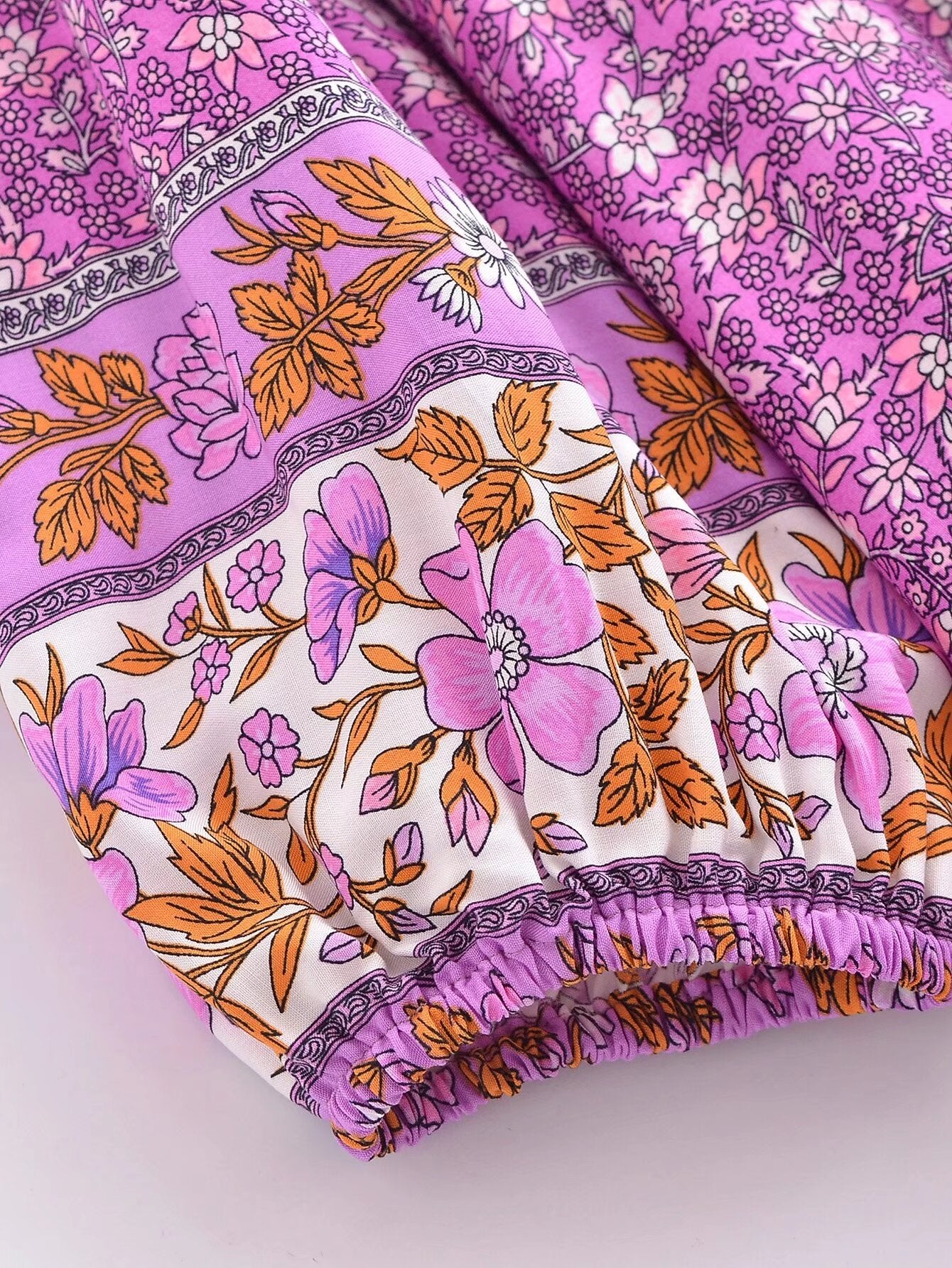Close-up of pink and orange floral pattern fabric on Malbusaat floral tie-neck maxi dress sleeve