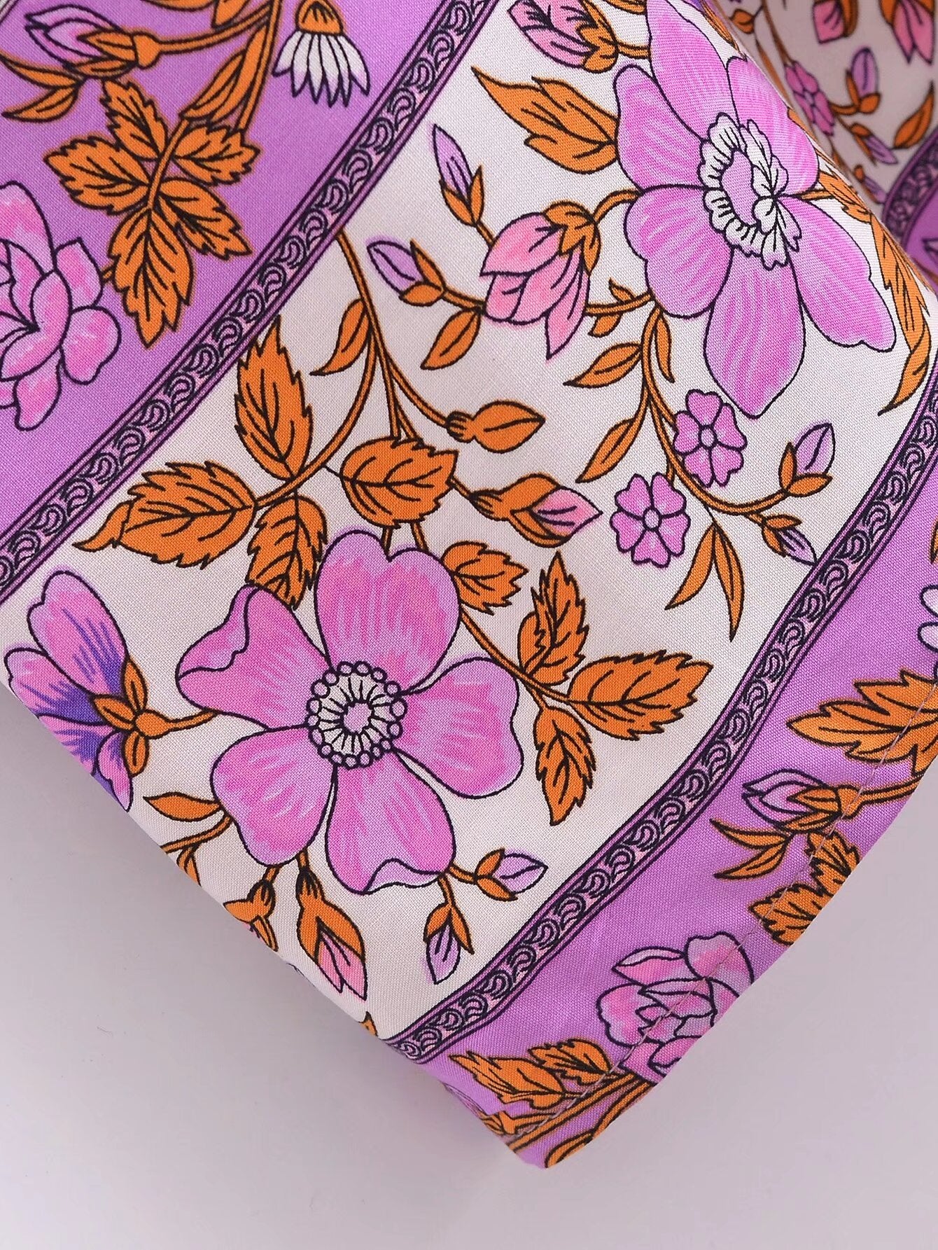 Close-up of Malbusaat floral tie-neck maxi dress fabric with pink flowers and orange leaves print