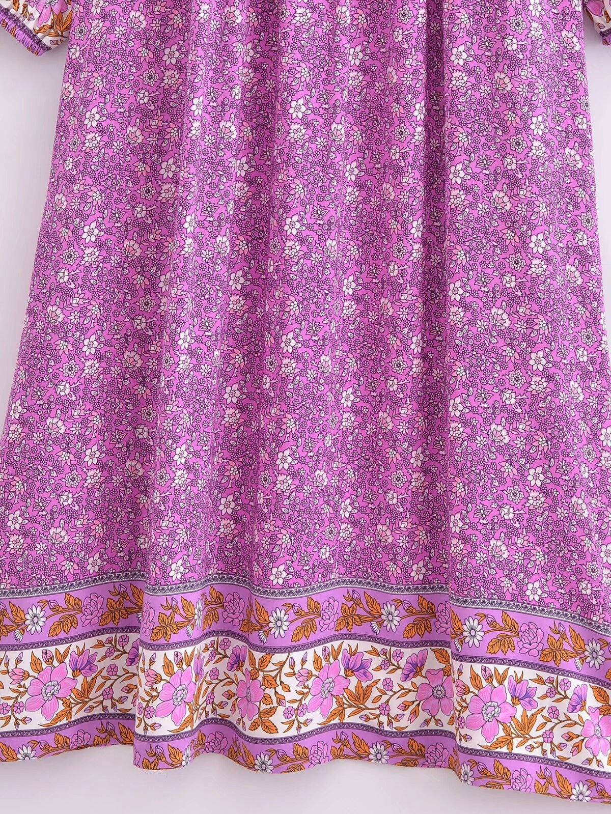Close-up of Malbusaat's purple floral tie-neck maxi dress featuring small floral patterns and decorative border print