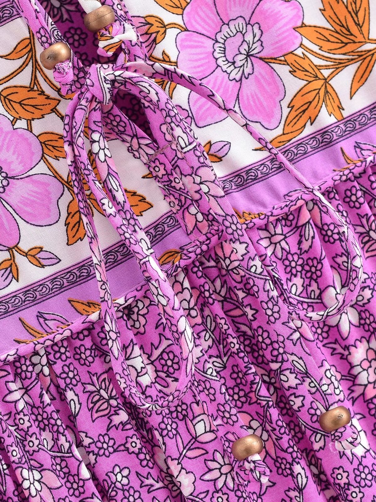 Close-up of purple floral tie-neck maxi dress with wooden bead details from Malbusaat