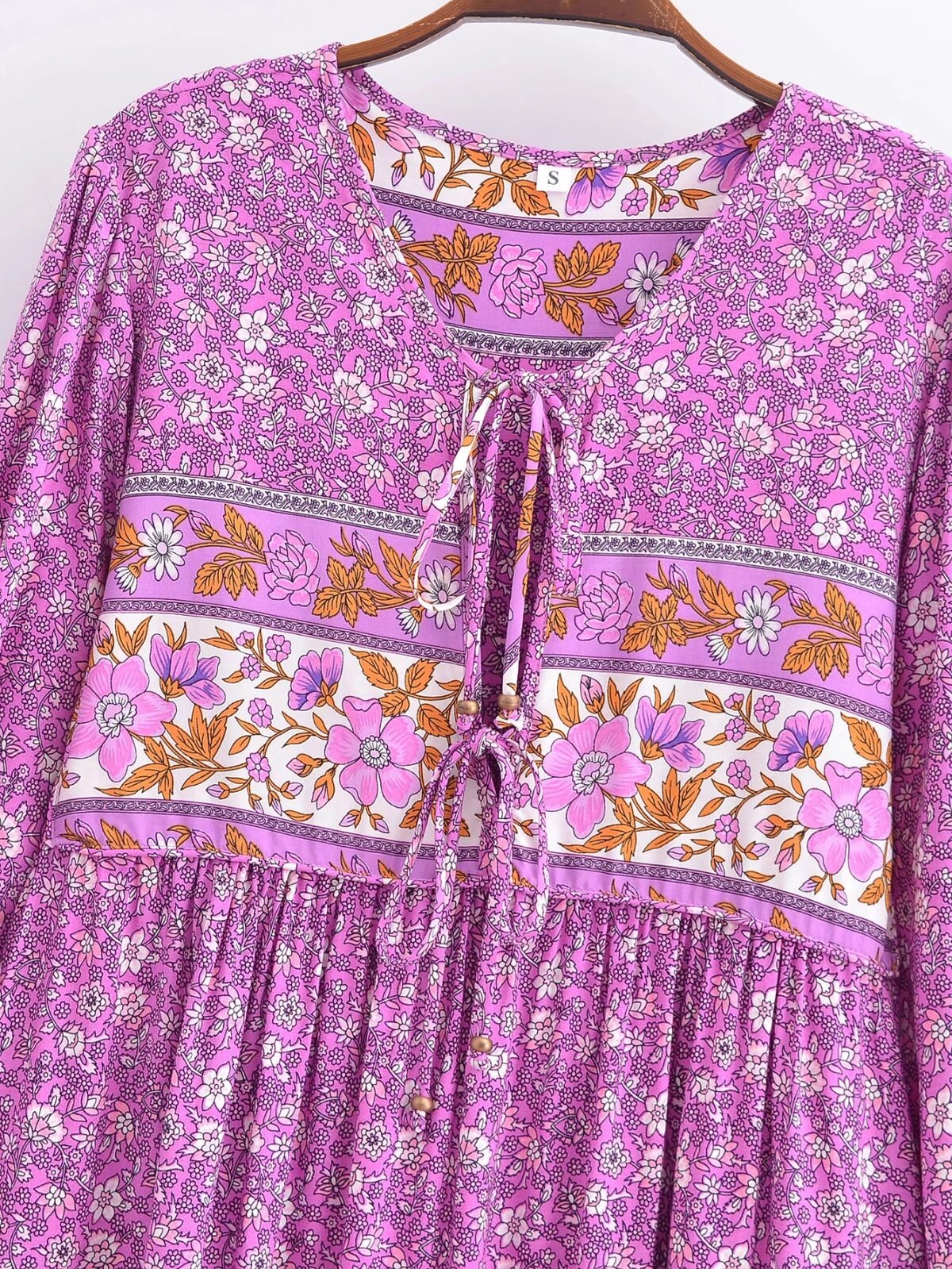 Purple floral tie-neck maxi dress with pink and white flower patterns and long sleeves by Malbusaat
