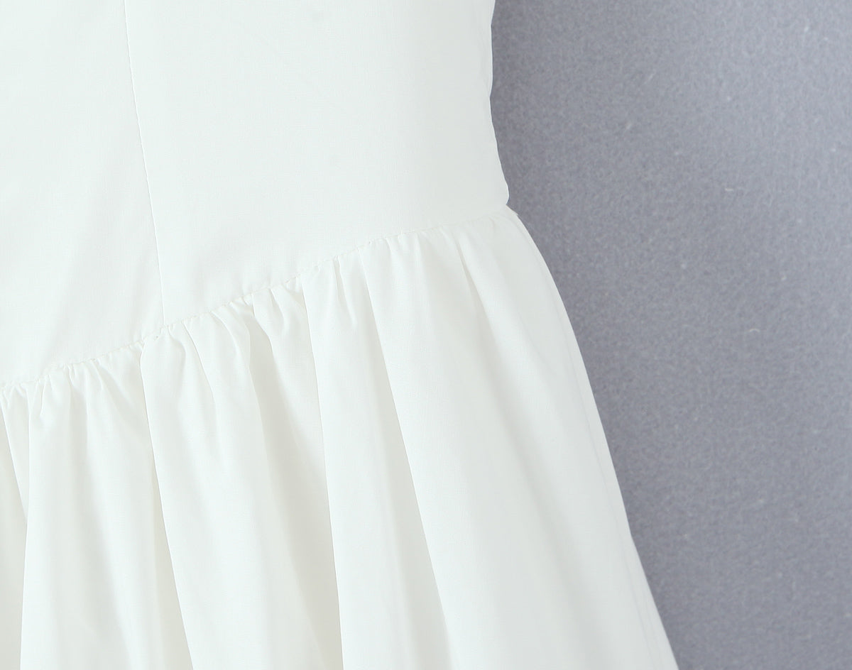 Malbusaat white French bowknot spaghetti dress close up of gathered skirt seam and flowing ruffle on grey background