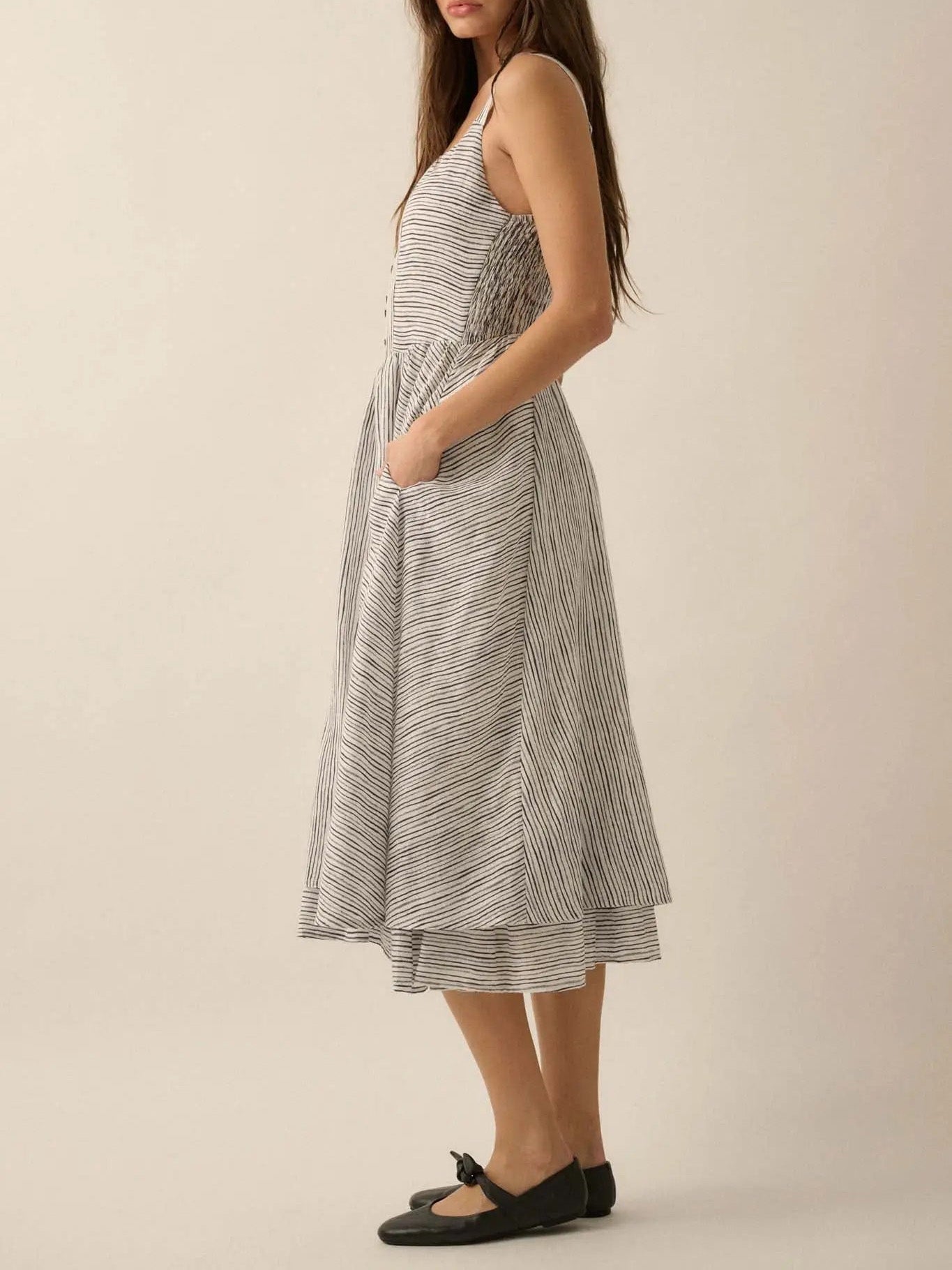 Side view of a ladies summer striped cotton dress featuring thin straps and a layered hem