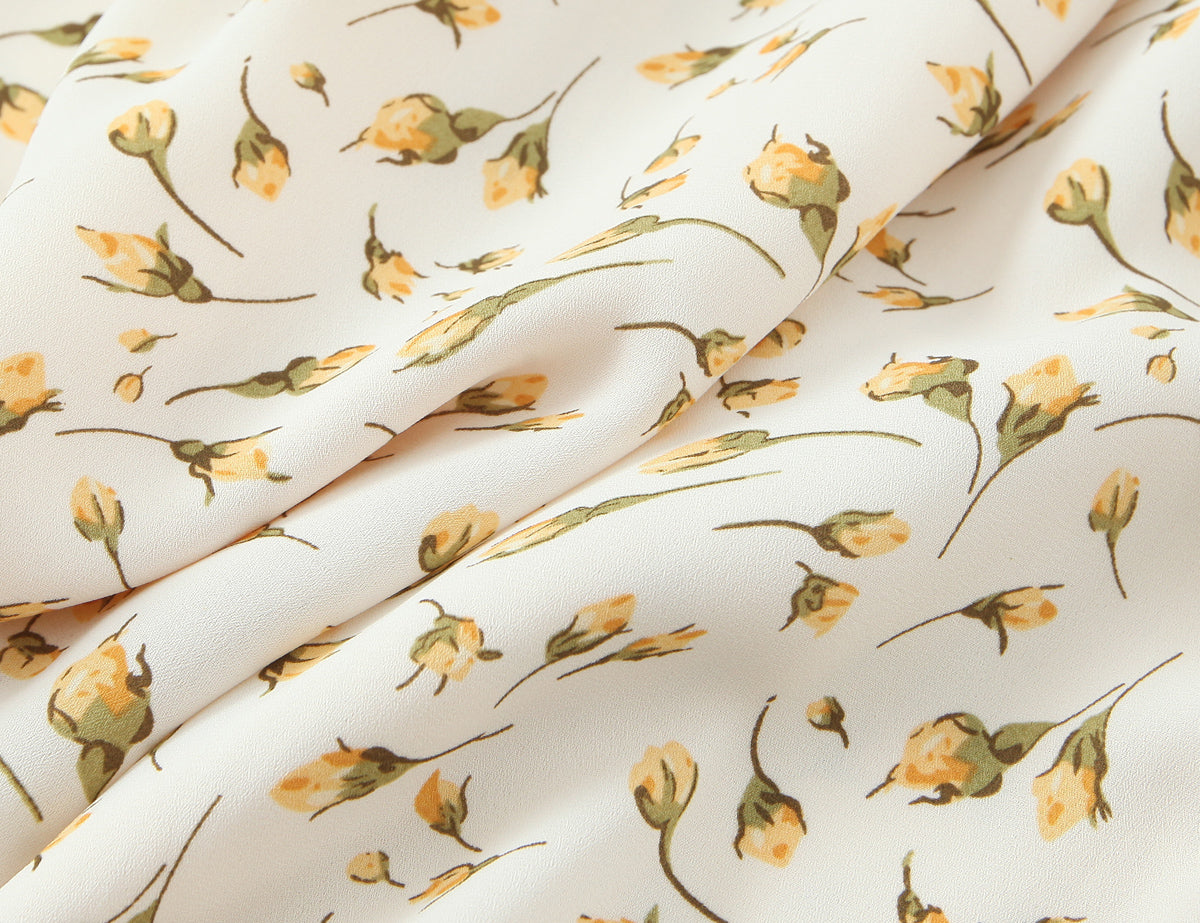 Close-up of fabric with floral print for Malbusaat summer floral puff sleeve dress in soft yellow and green tones