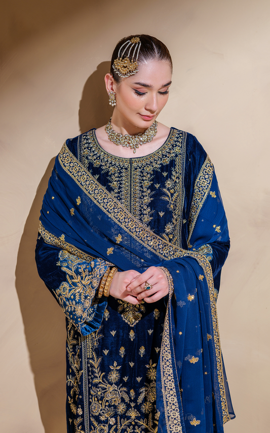 Elegant model wearing a midnight blue velvet Pakistani suit adorned with intricate gold embroidery