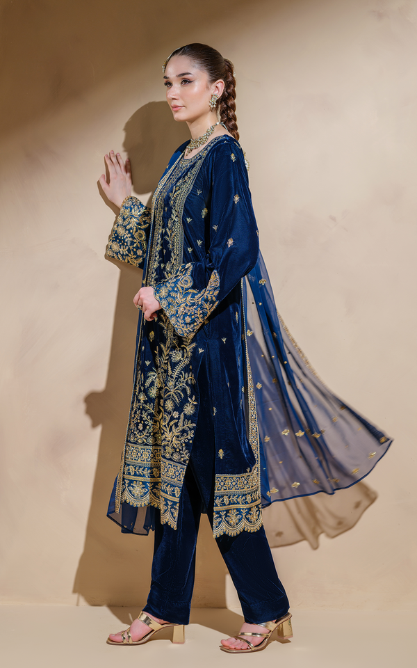 Elegant midnight blue velvet Pakistani suit with intricate gold embroidery and flowing chiffon dupatta