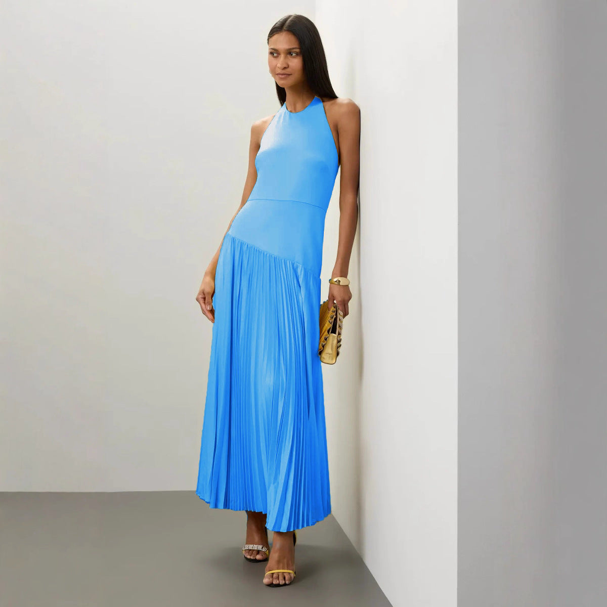 Woman wearing a blue Malbusaat Pleated Halter Dress for Summer with pleated skirt and halter neckline