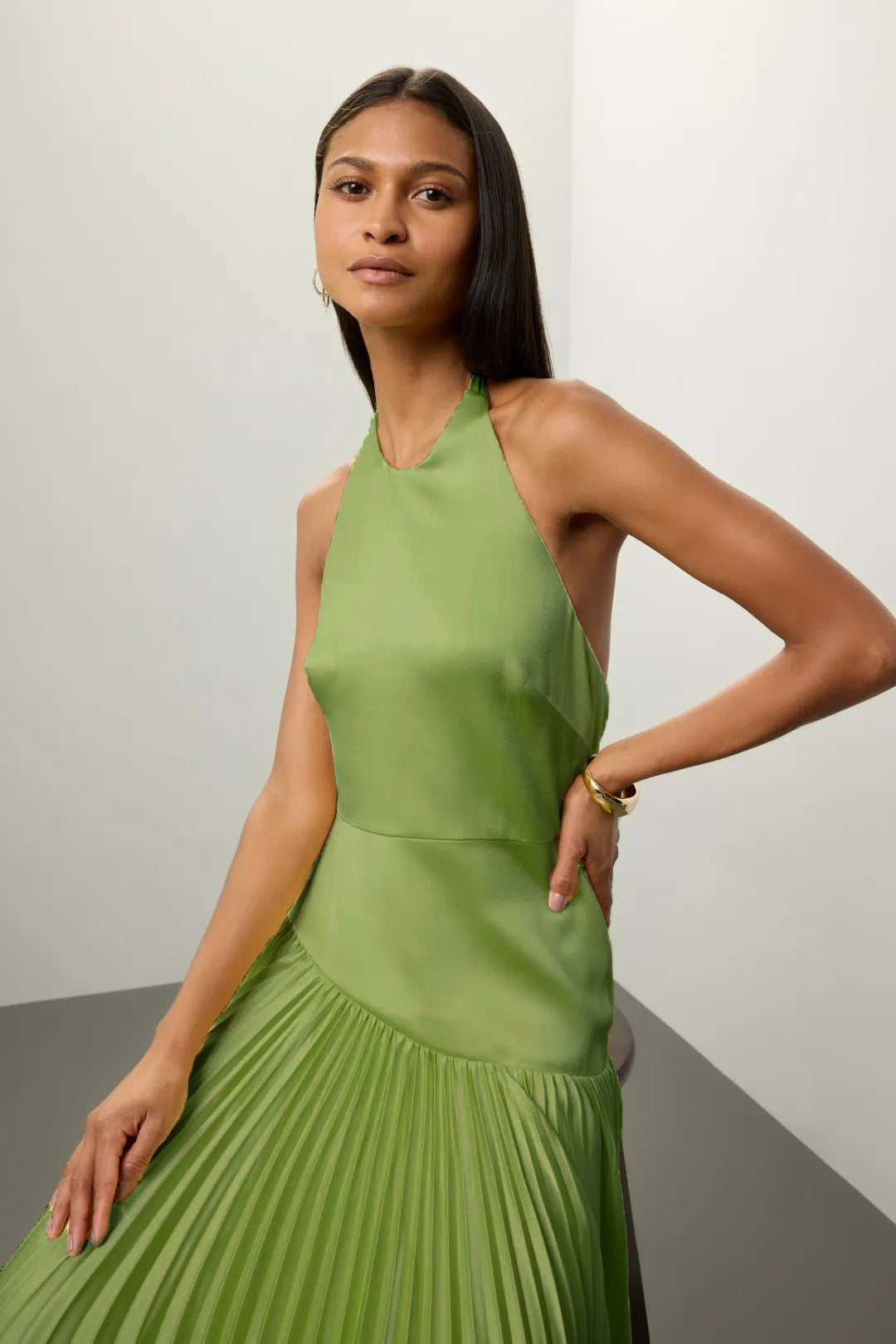 Woman wearing Malbusaat green Pleated Halter Dress for Summer with sleeveless design and flowy skirt