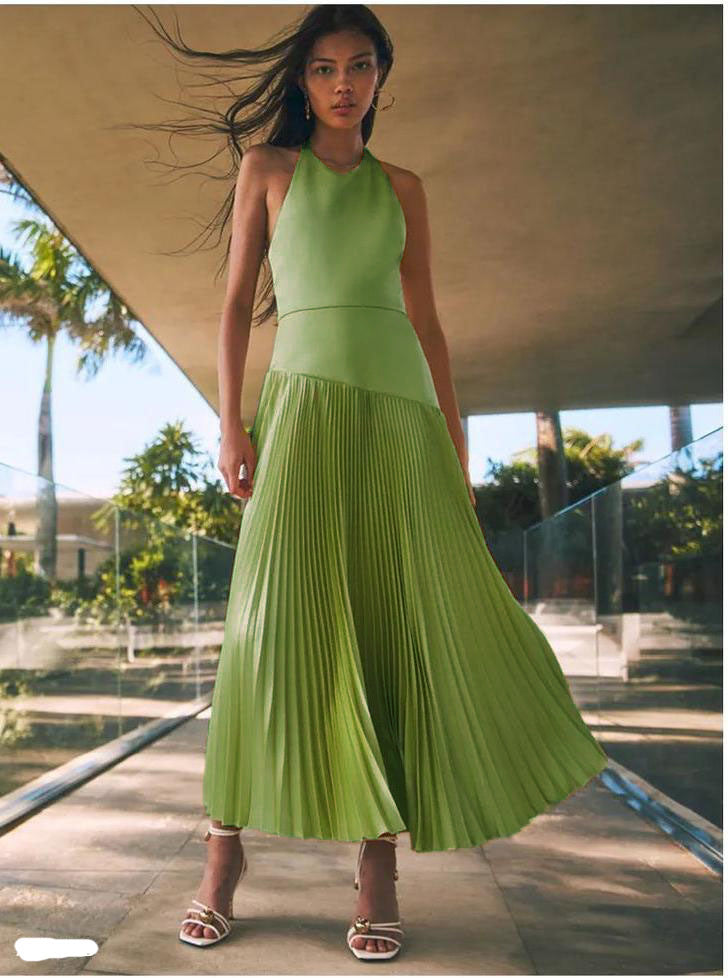 Woman wearing a green pleated halter dress for summer standing outdoors with breeze
