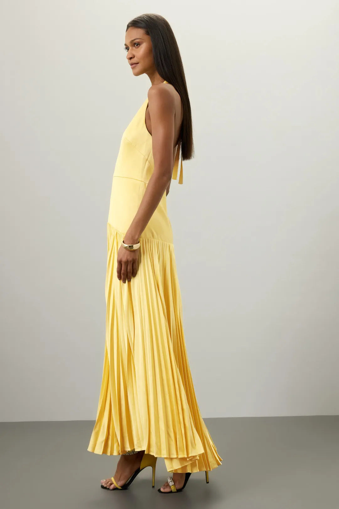 Malbusaat yellow pleated halter dress for summer with flowing skirt worn by model