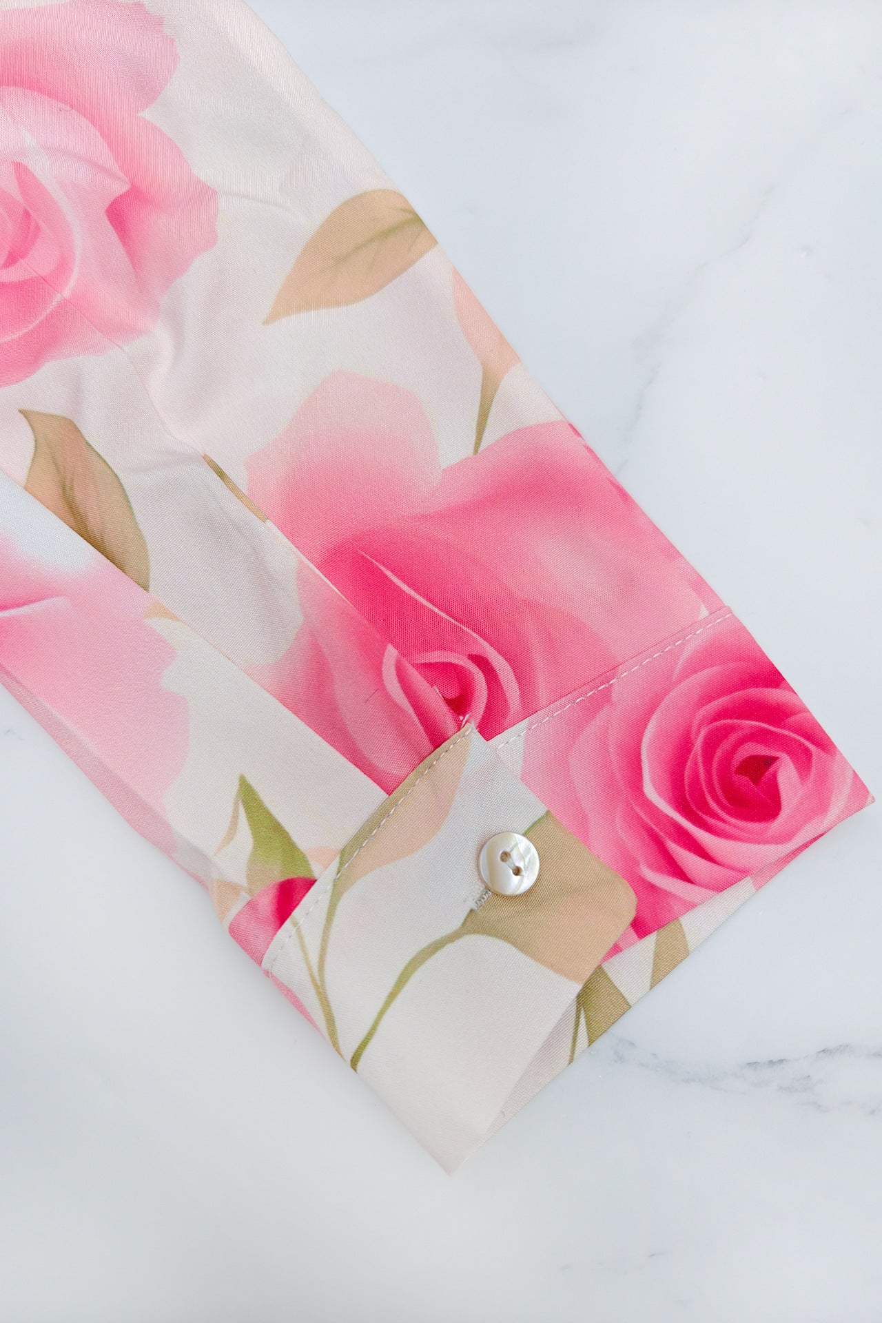 Close-up of sleeve detail on a printed pleated maxi dress featuring pink rose patterns