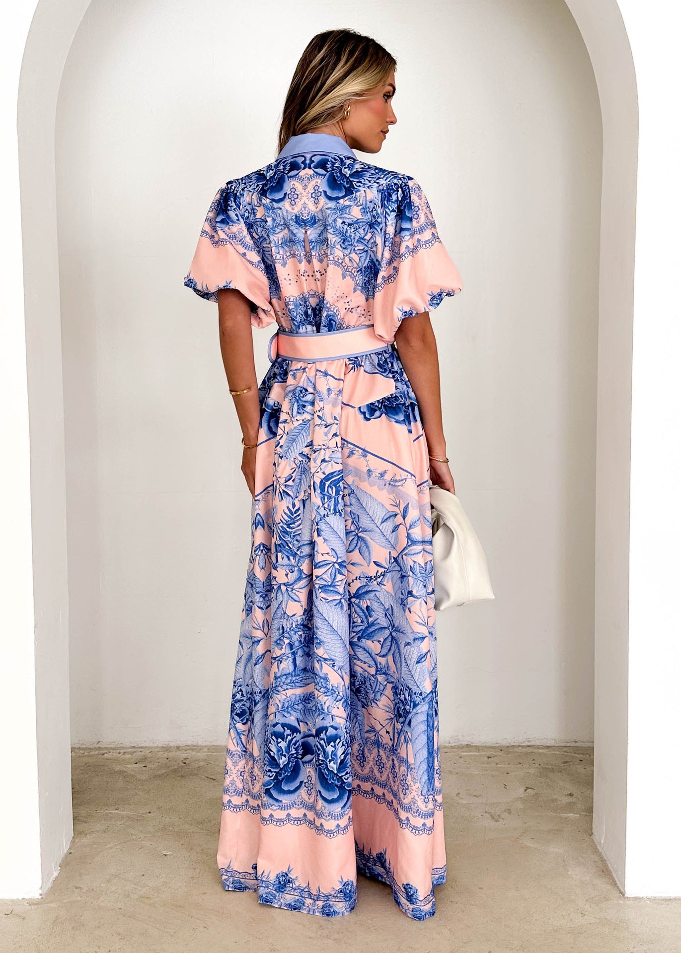 Woman wearing Malbusaat stand collar ruffle top with blue and pink floral patterns from the back