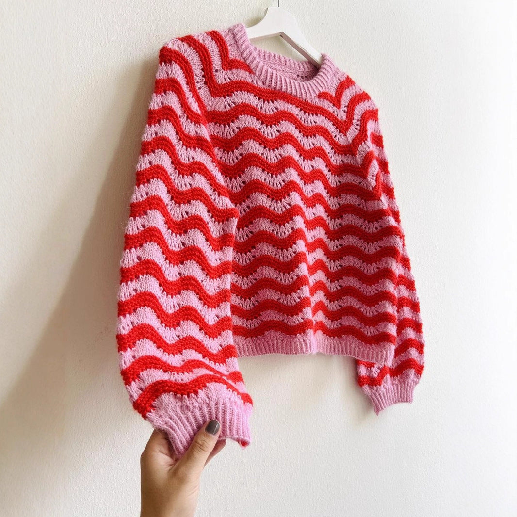 Striped knit sweater for women in pink and red wavy pattern with long sleeves hanging on white hanger