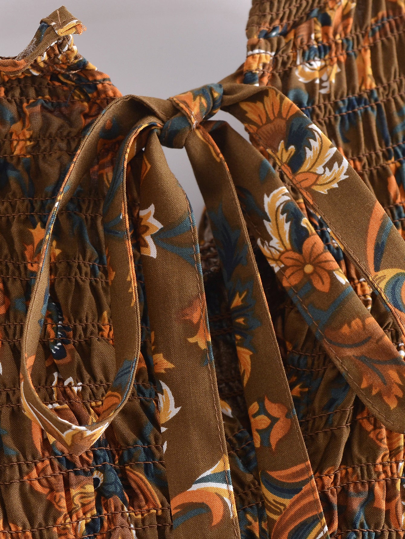 Close-up of floral fabric and tied bow detail on Malbusaat summer printed midi dress
