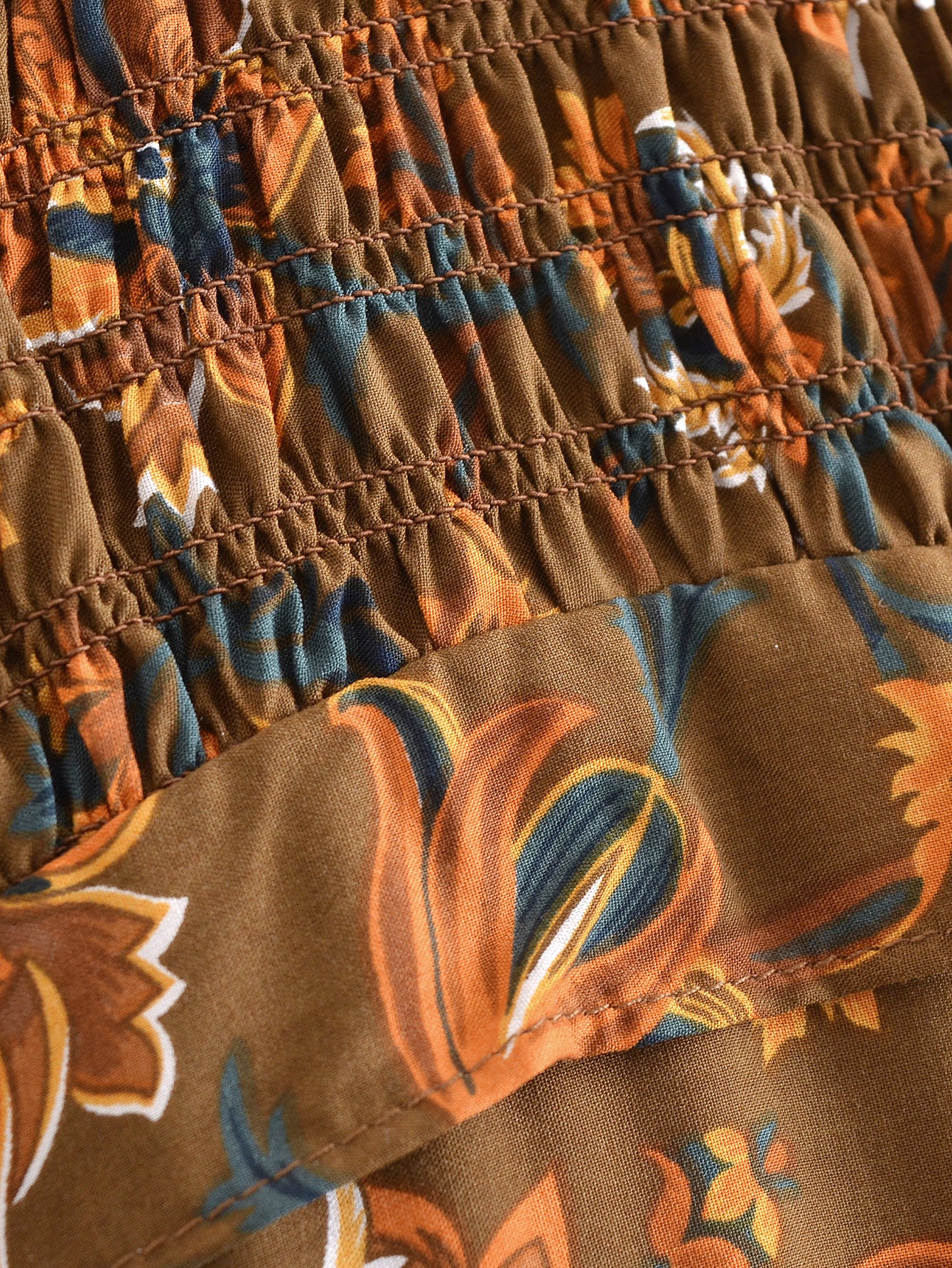 Close-up of floral fabric detail on Malbusaat summer printed midi dress with brown and orange tones