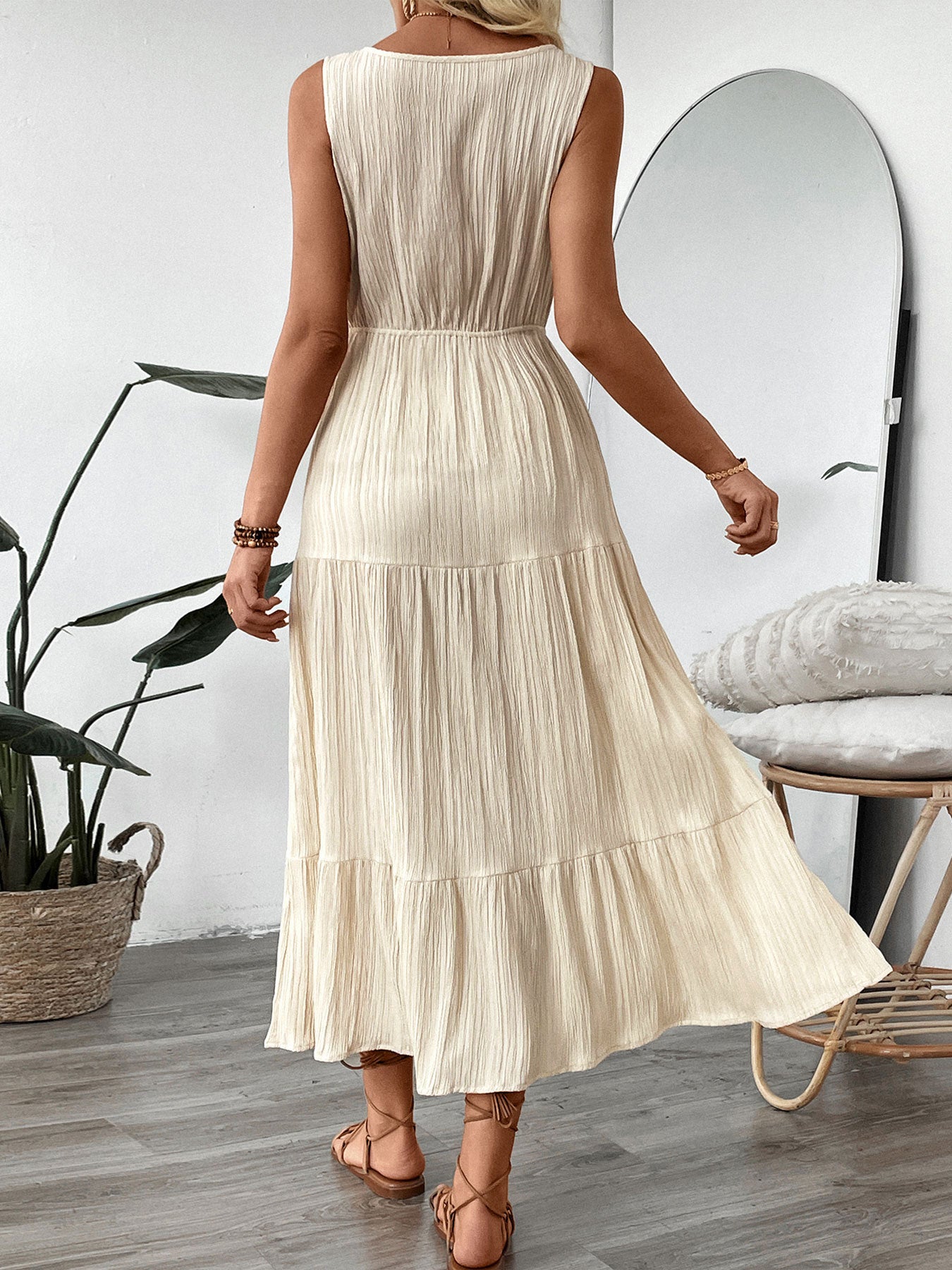 Back view of a woman wearing a cream summer V-neck maxi dress by Malbusaat with a tiered pleated skirt