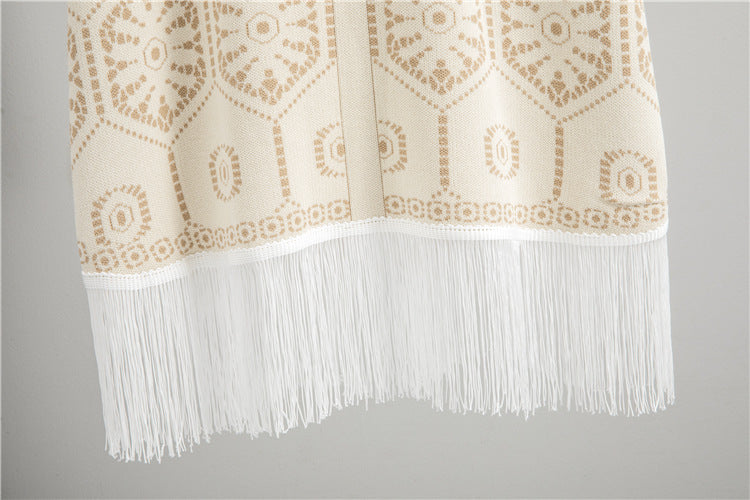 Close-up of delicate fringe detail on a cream tassel button knit dress with intricate patterns