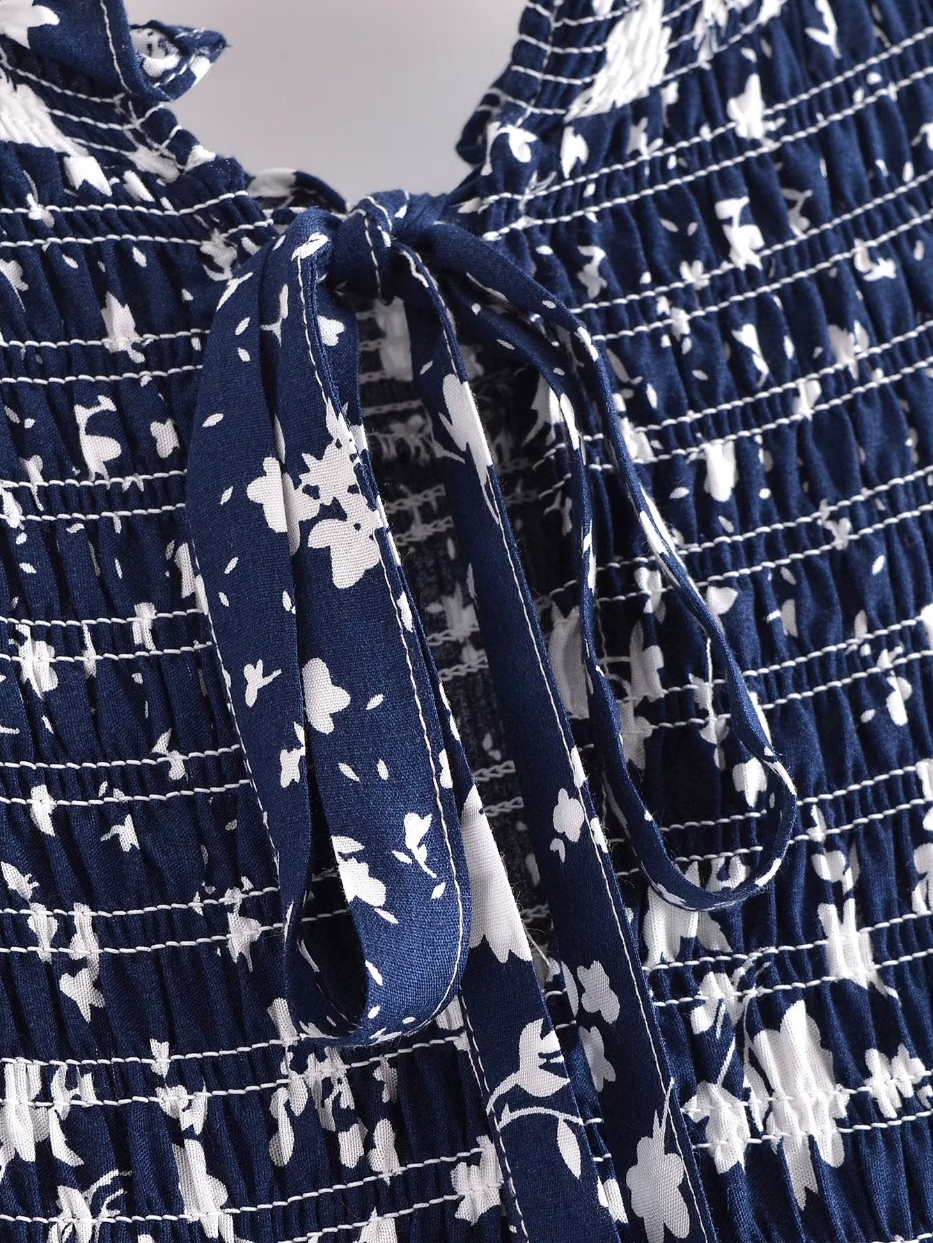 Close-up of blue and white Malbusaat women's summer floral dress with detailed tie and stitching