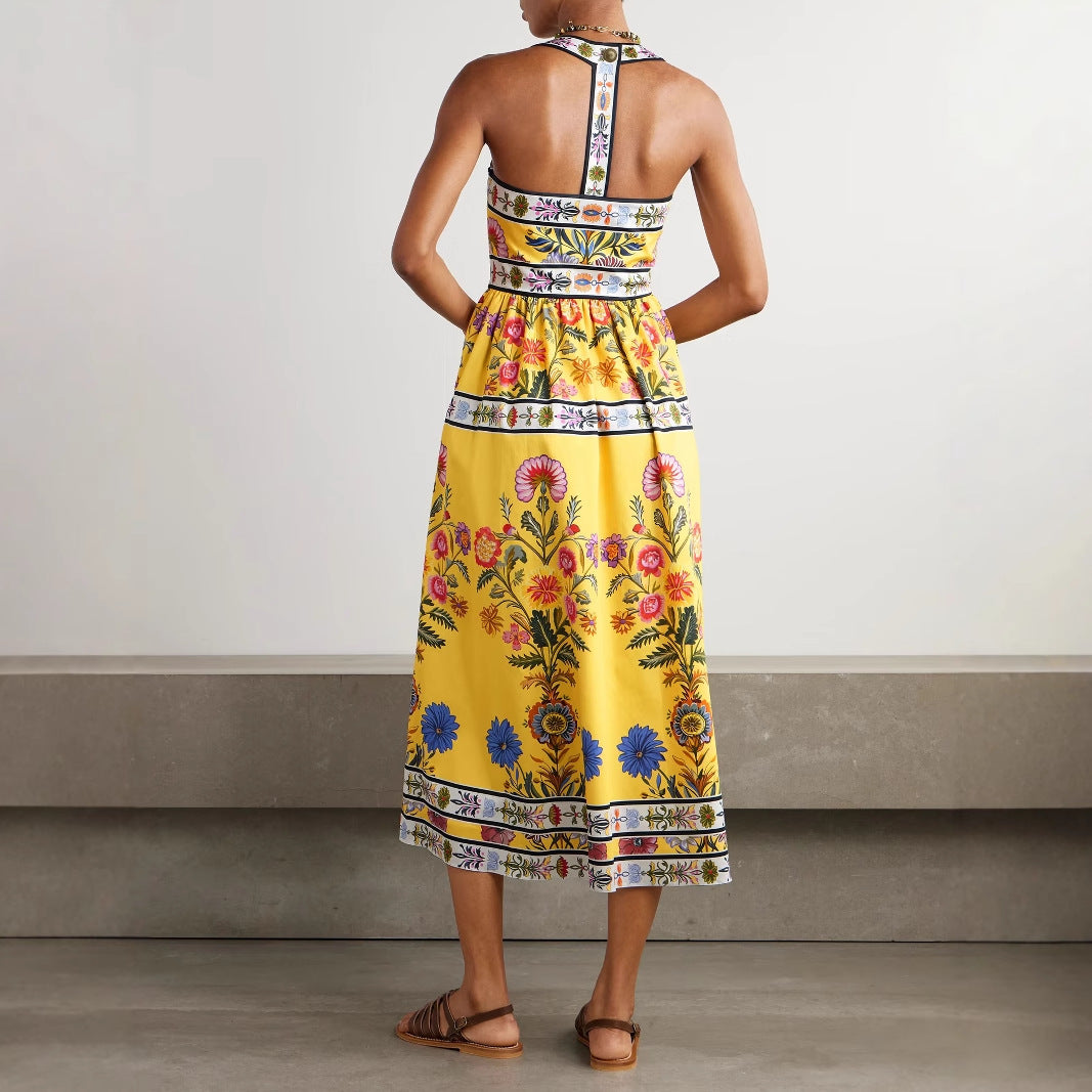 Back view of a yellow printed midi dress with pockets by Malbusaat featuring floral patterns and a halter neck design