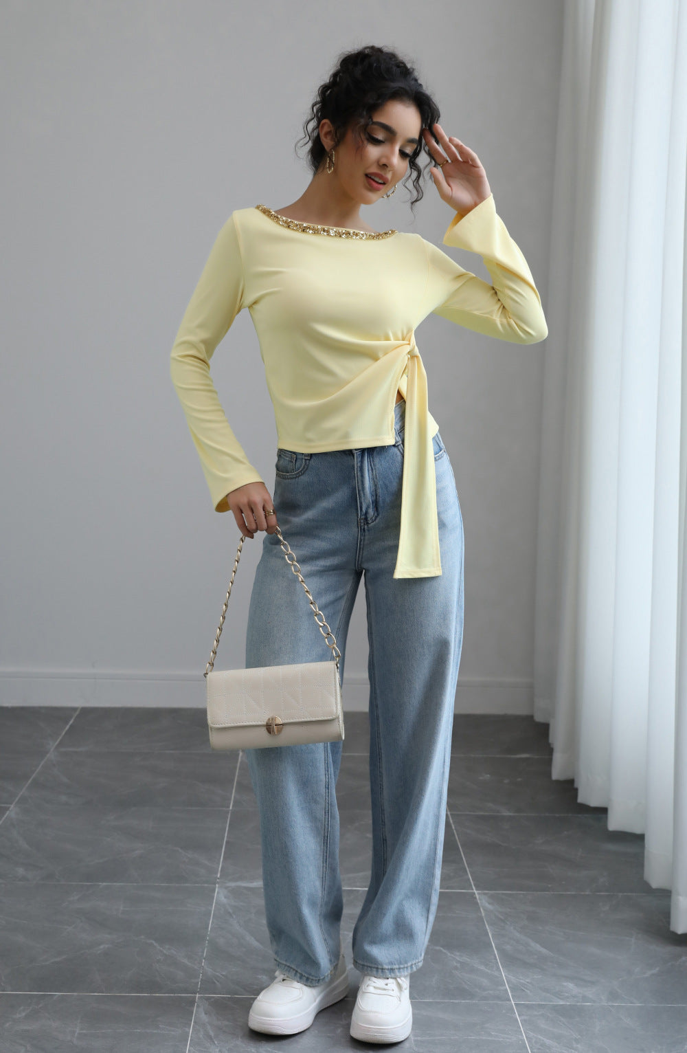 Malbusaat model wearing autumn lace up top in pale yellow with side tie embellished neckline and jeans