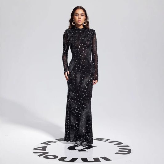 Malbusaat model wearing a floor length black rhinestone bodycon dress with long sleeves and high neck