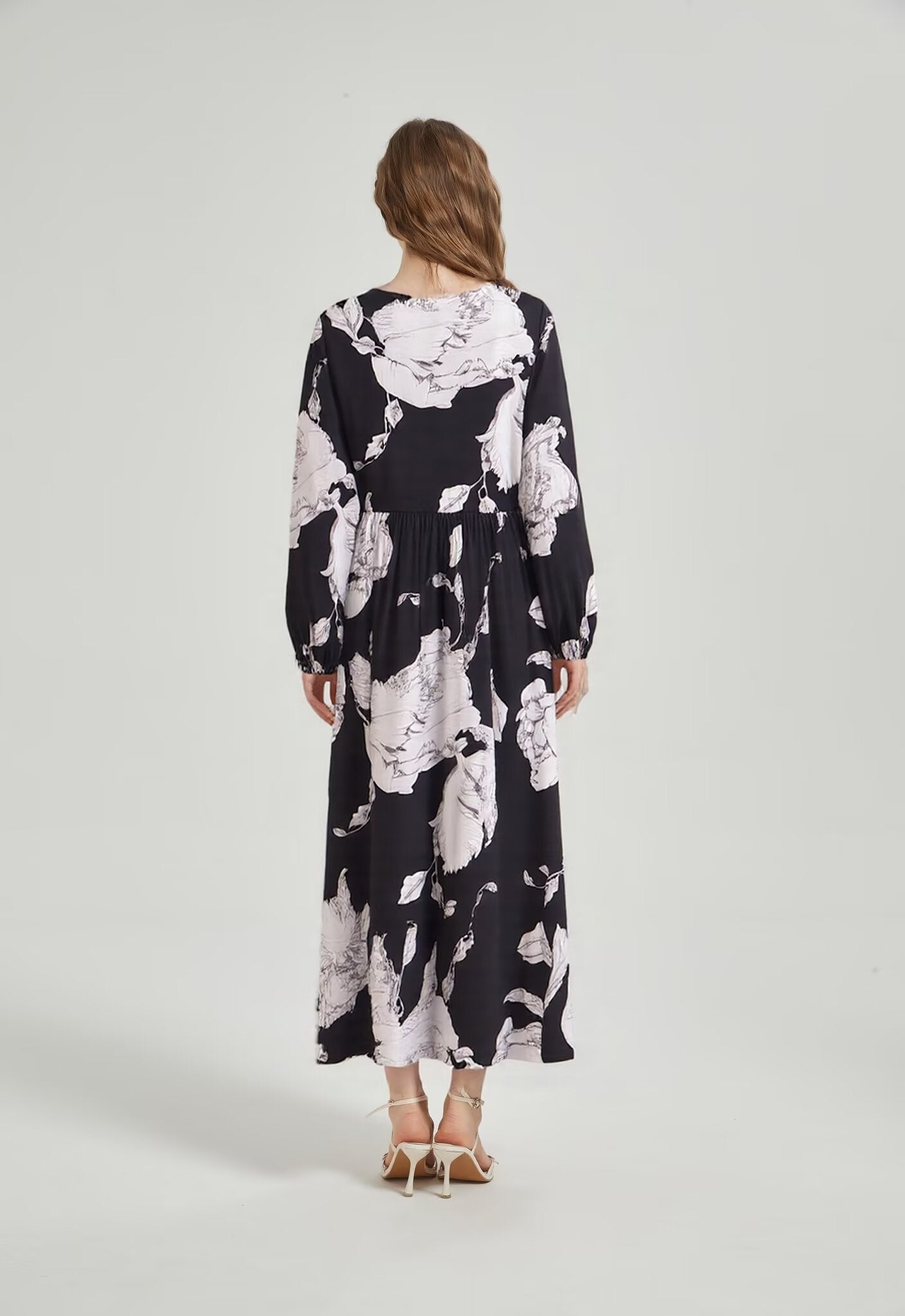 Back view of Malbusaat bohemian loose midi dress in black with white floral print and long sleeves