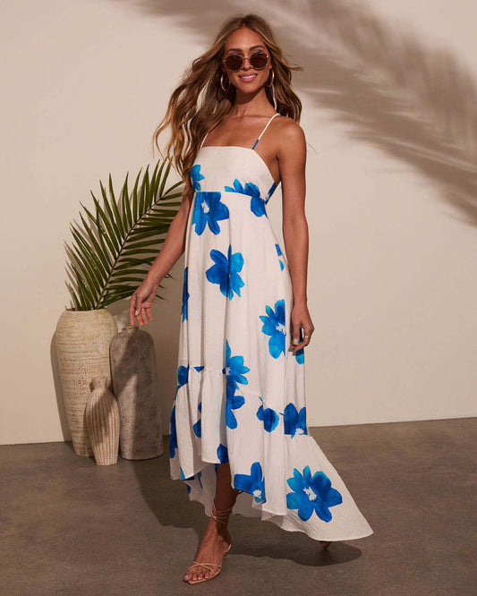 Woman wearing a bohemian summer floral maxi dress with blue flowers and spaghetti straps