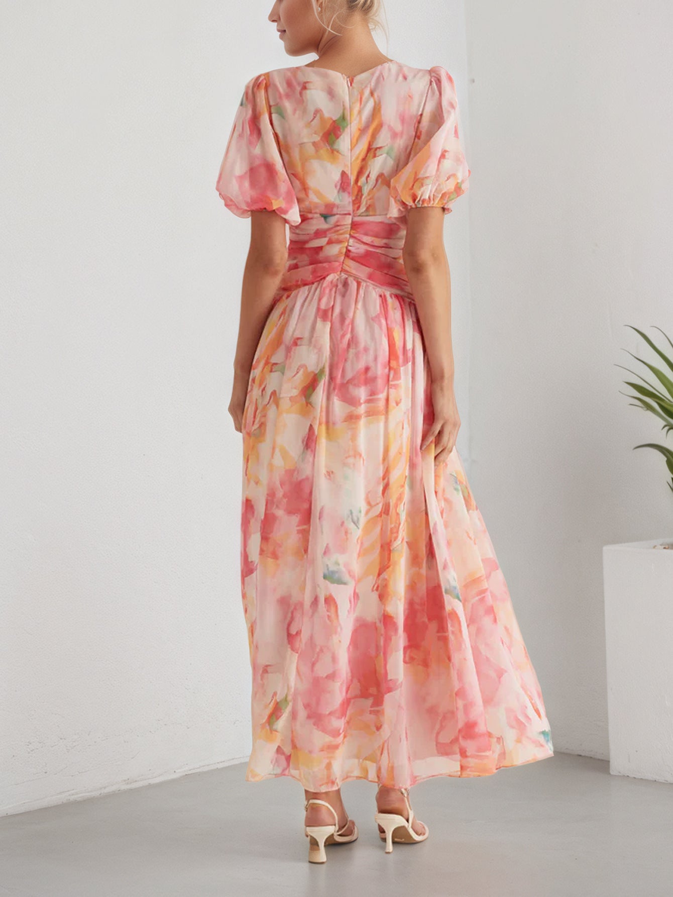 Back view of a floral chiffon maxi dress in pastel colours, featuring puff sleeves and a cinched waist