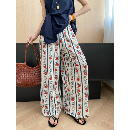 Cream floral vertical stripe loose straight wide pants for women styled with navy sleeveless top and woven bag