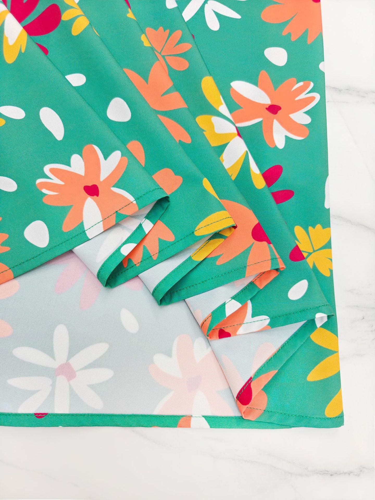 Close-up of off shoulder floral midi dress fabric featuring vibrant flowers on a teal background