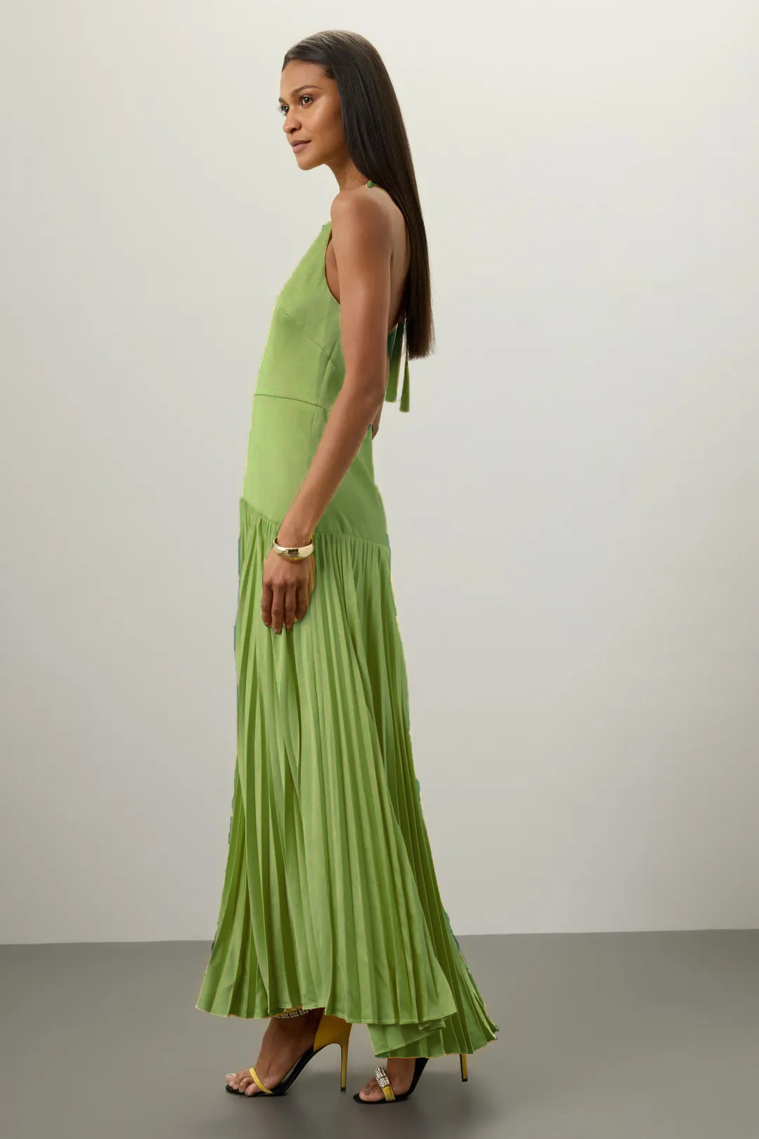 Woman wearing a green Pleated Halter Dress for Summer with high heels against a plain background