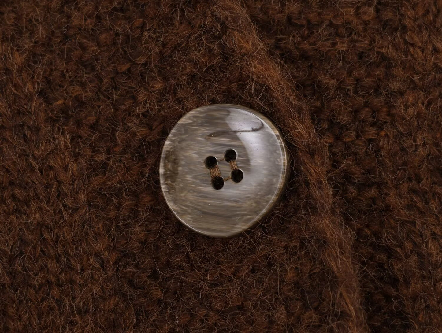 Close-up of a brown button on a retro v neck knit cardigan by Malbusaat