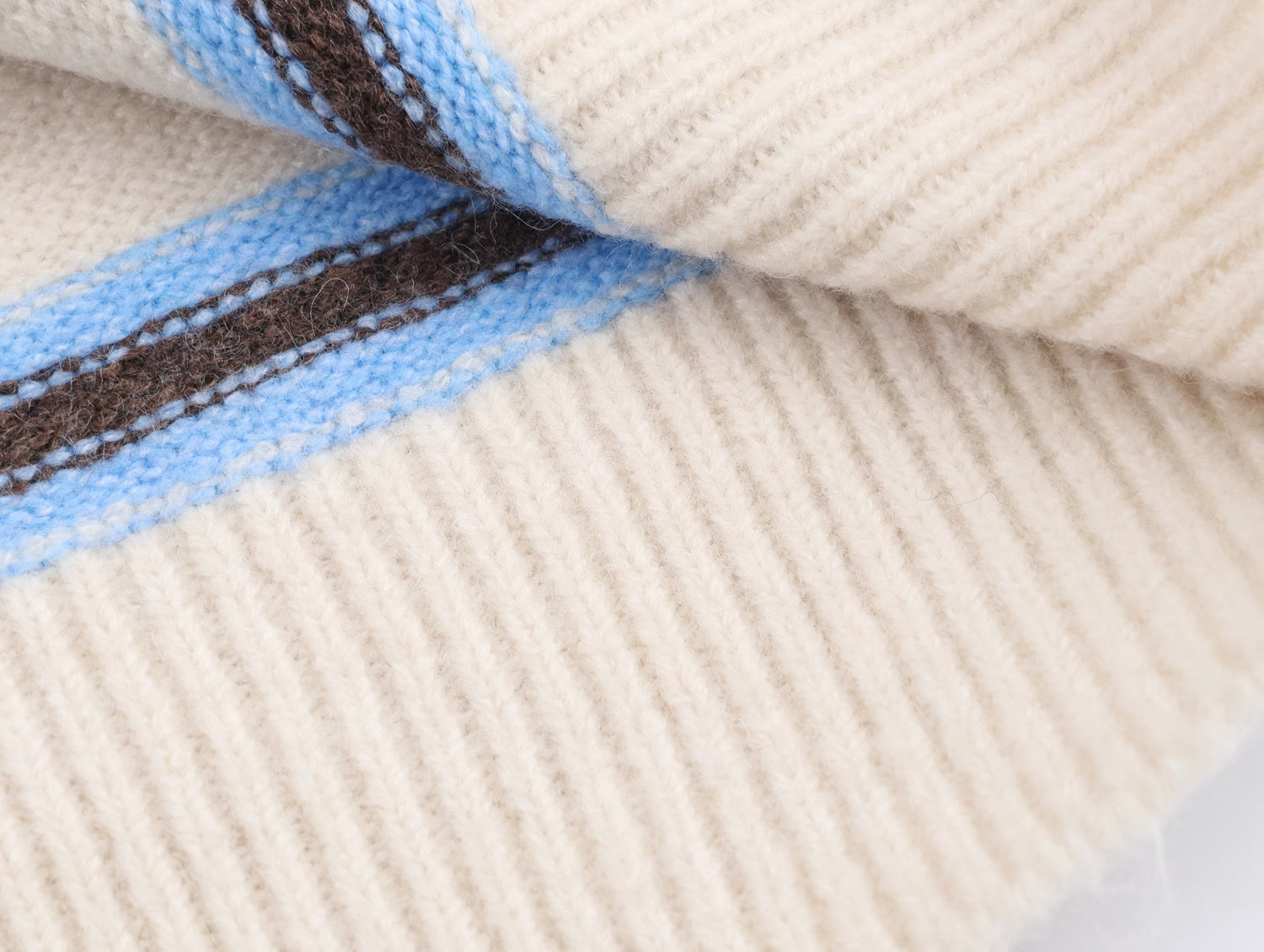 Close-up of a striped polo knit pullover for women with warm beige and blue stripes