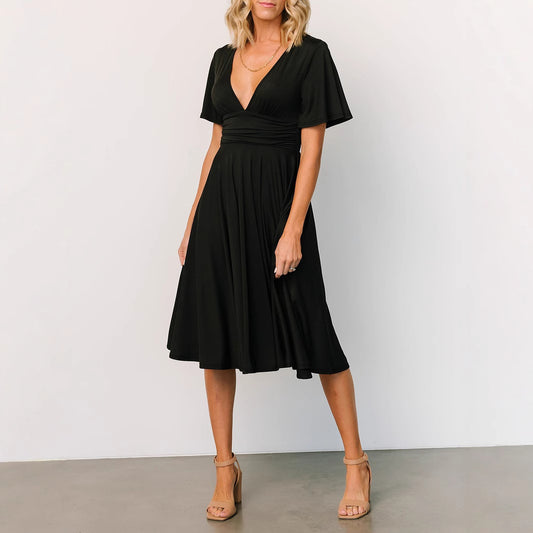 Black summer V neck dress for women with short sleeves and midi length styled with nude heels